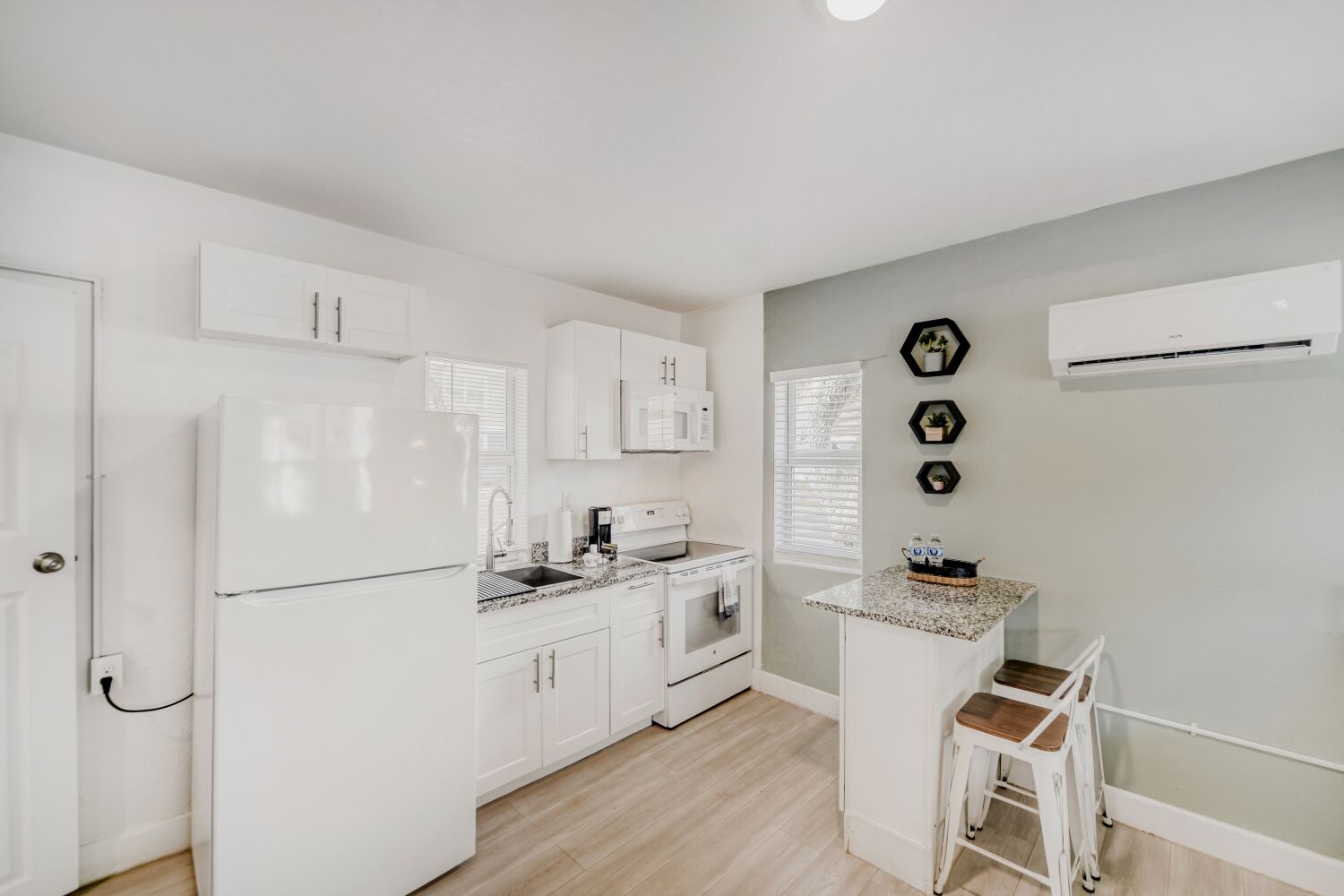 image Sleek kitchen offers a refrigerator, oven, stovetop, microwave, and breakfast bar, making home-cooked meals a breeze in a bright, welcoming space.