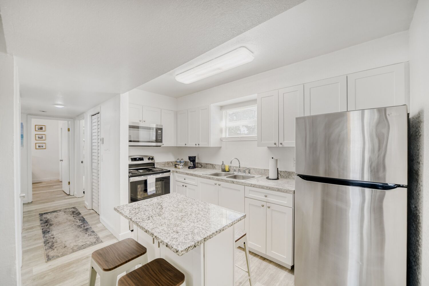 image Sleek kitchen boasts stainless steel appliances, granite countertops, a coffee maker, and breakfast bar seating for effortless dining and cooking.