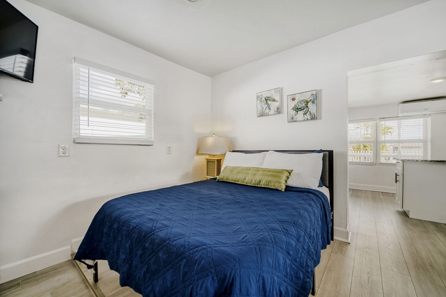 image Serene sleeping area offers a plush bed with crisp linens, curtains, and a wall-mounted TV for restful nights and easy mornings.