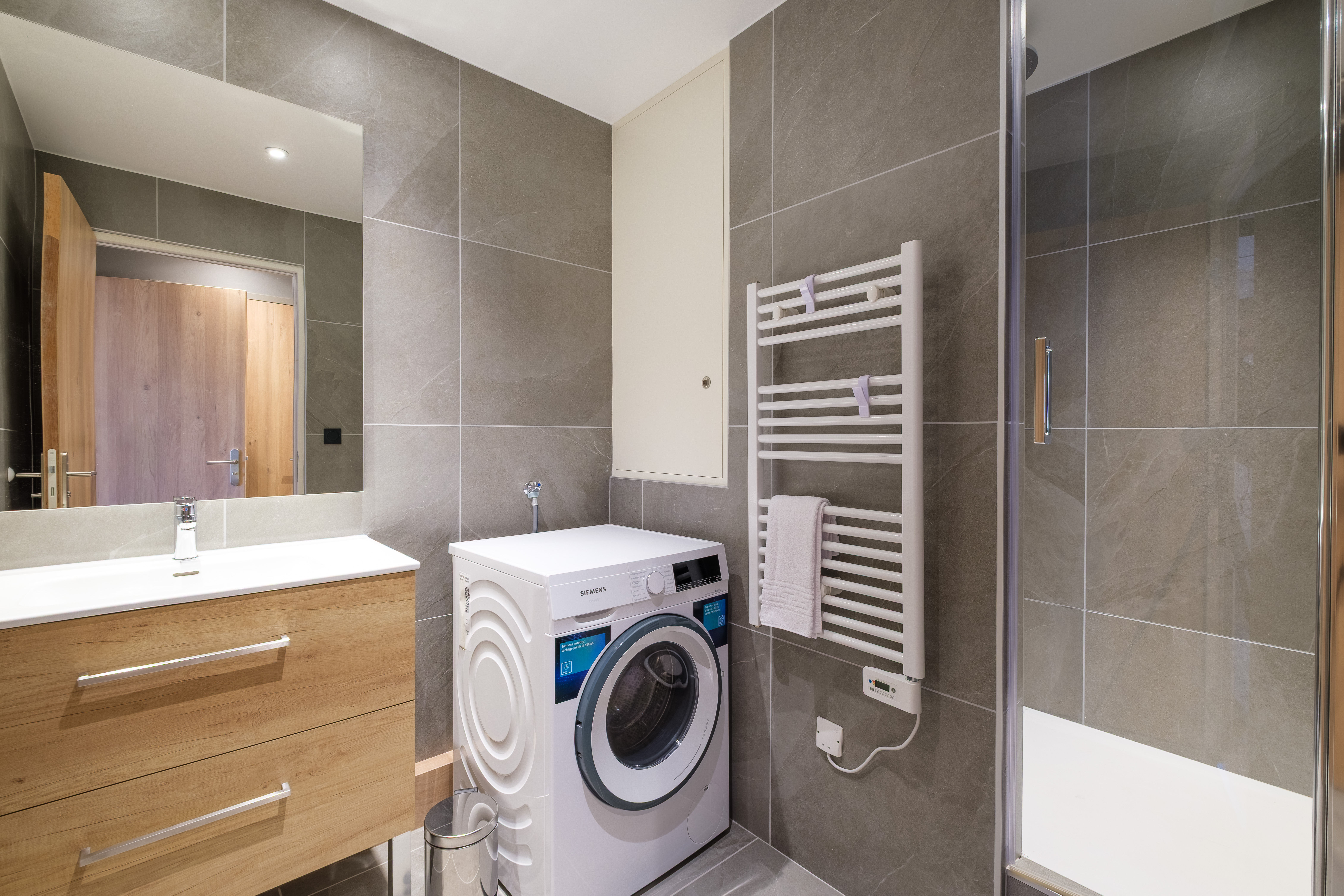 image The contemporary bathroom features sleek grey tiling, a spacious shower, and modern amenities for everyday convenience.