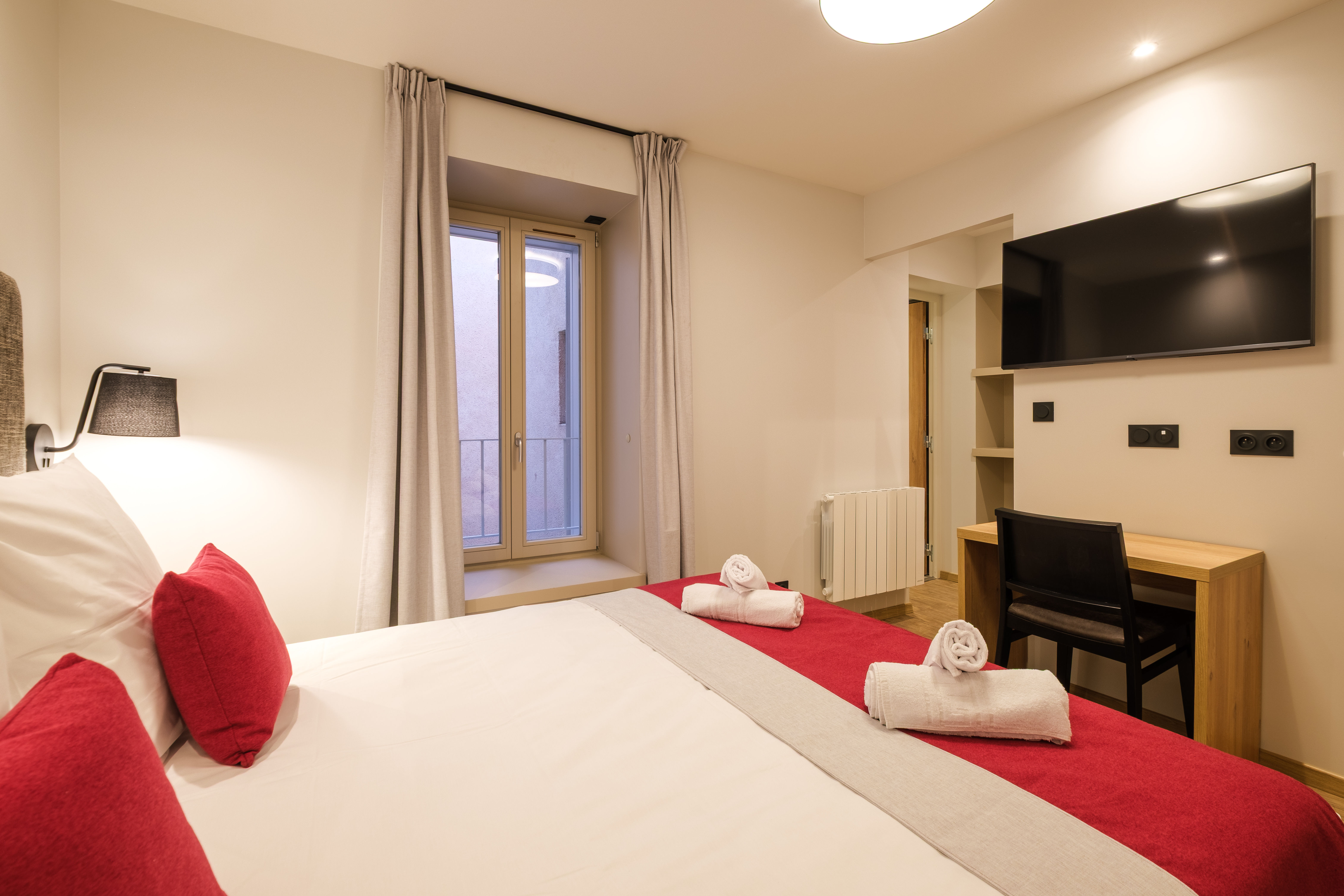 image The cosy double bedroom is tastefully decorated and includes a TV, offering a comfortable retreat after a day exploring Lons-le-Saunier.