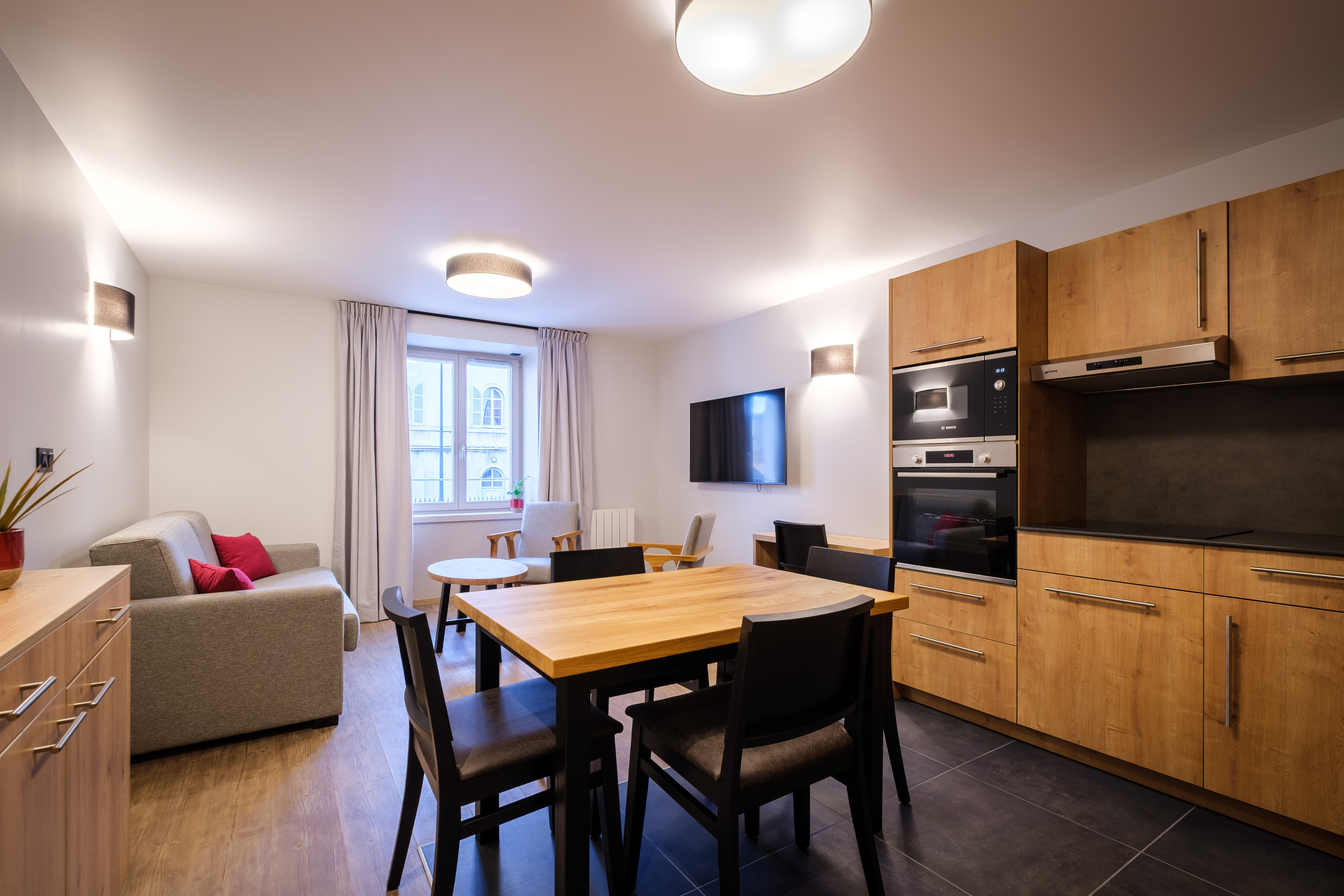 image The modern living area features a cosy sofa bed, dining space, and TV alongside the fully equipped kitchen, creating a bright and comfortable place to relax.