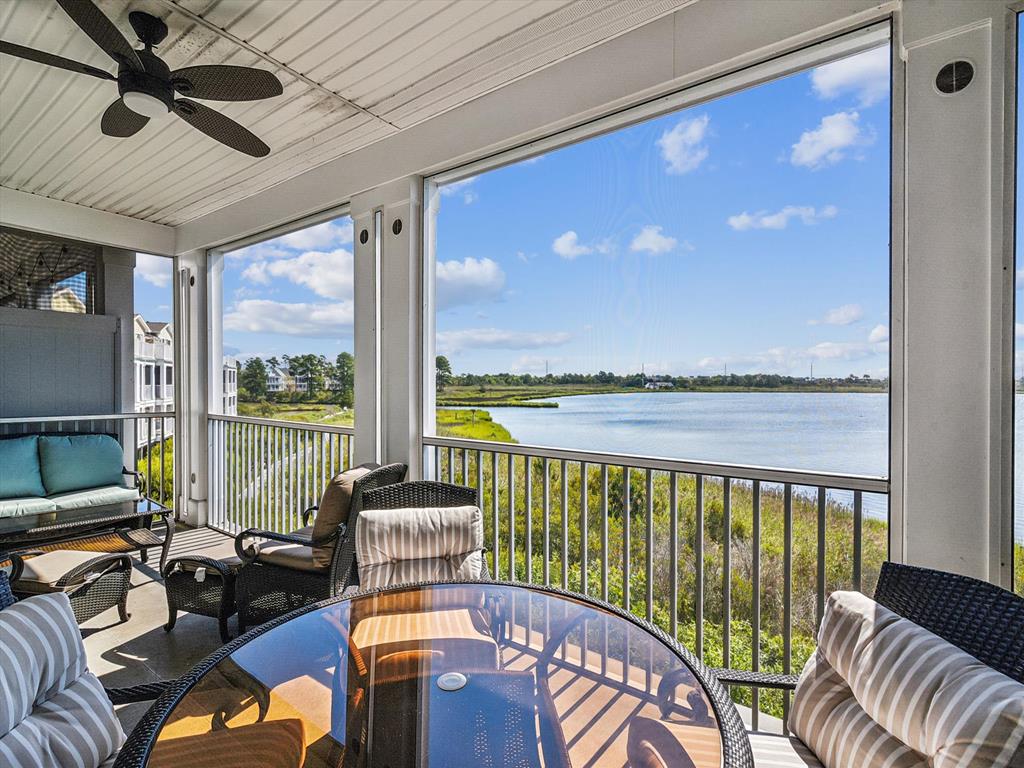 image The screened porch is set up for relaxed seating while overlooking calm water and surrounding greenery.