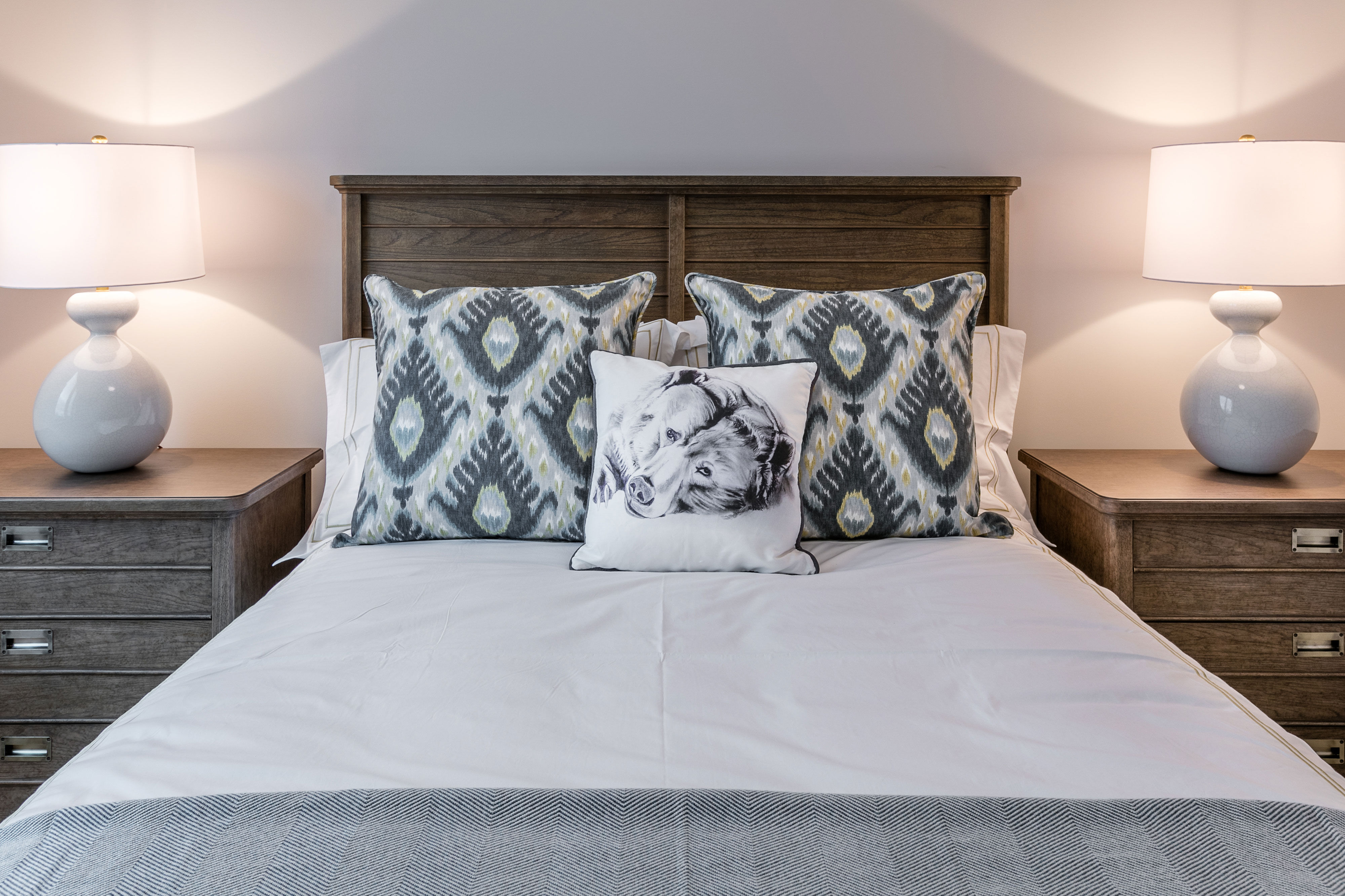 image A cozy bedroom is styled with plush bedding and warm lighting, creating a peaceful retreat after a day of skiing on Okemo Mountain.