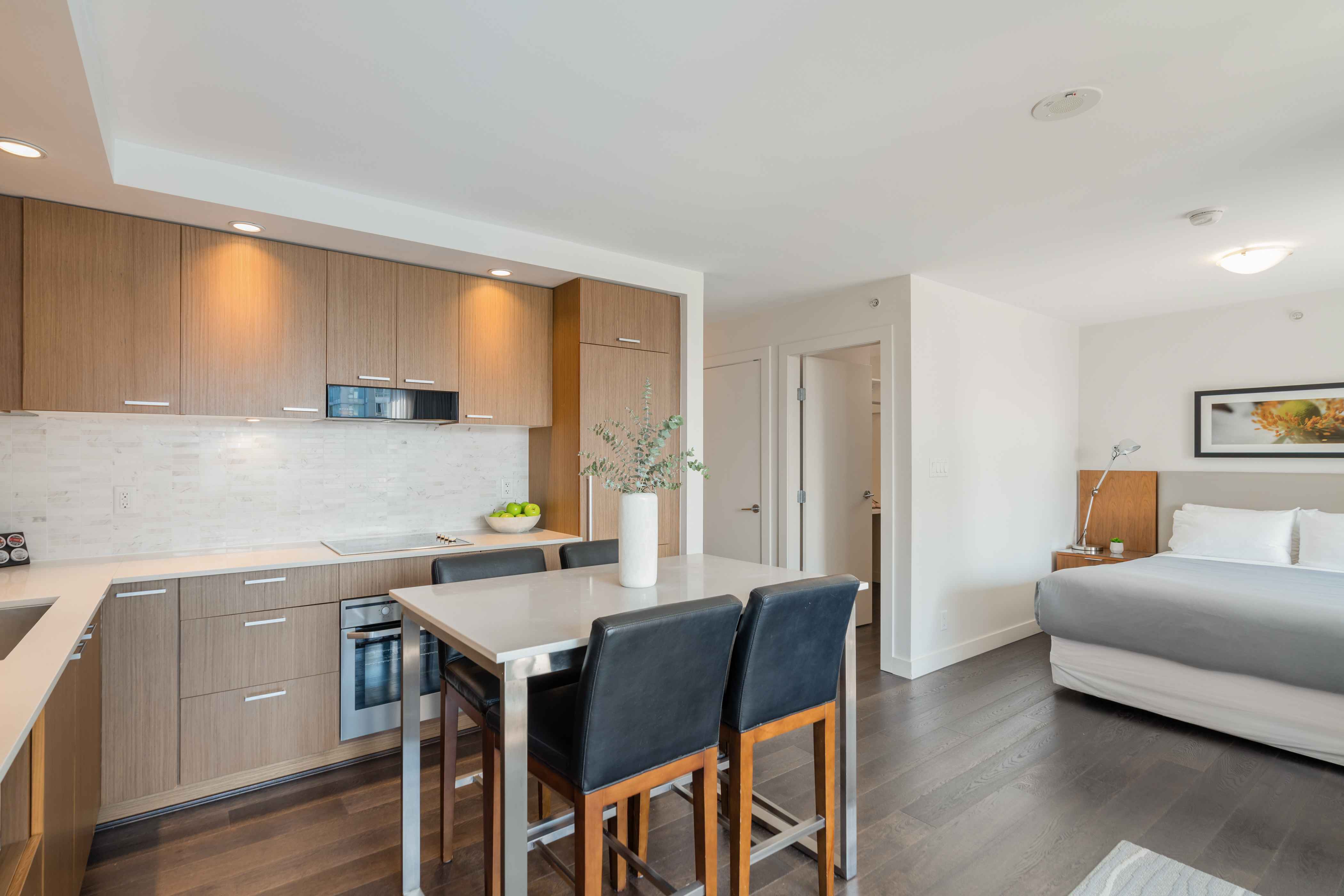 image Bright studio layout with a full kitchen, bar seating, and a cozy sleeping area designed for efficient city living.