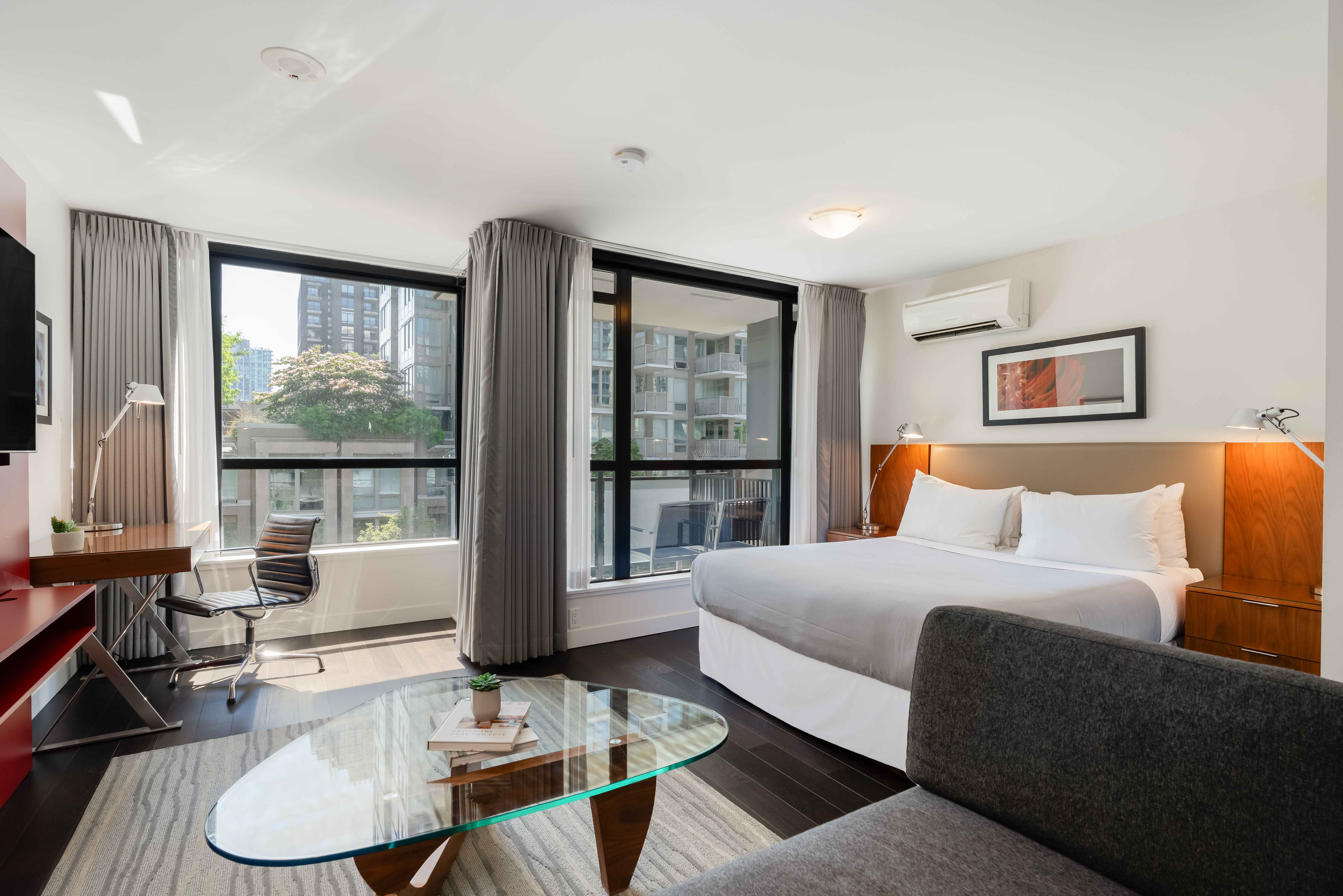 image Bright living room with a comfortable sofa, glass coffee table, and large windows bringing in natural light from downtown Vancouver.