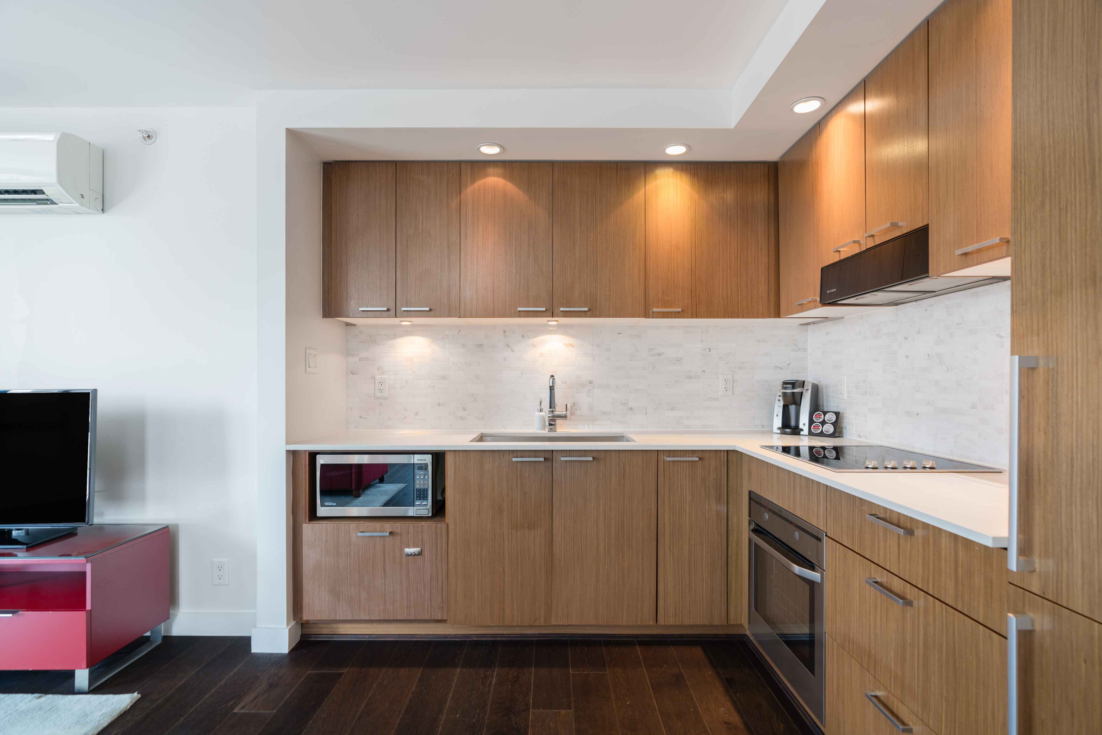 image Fully equipped modern kitchen featuring sleek cabinetry, stone countertops, and full-size appliances for extended stays.