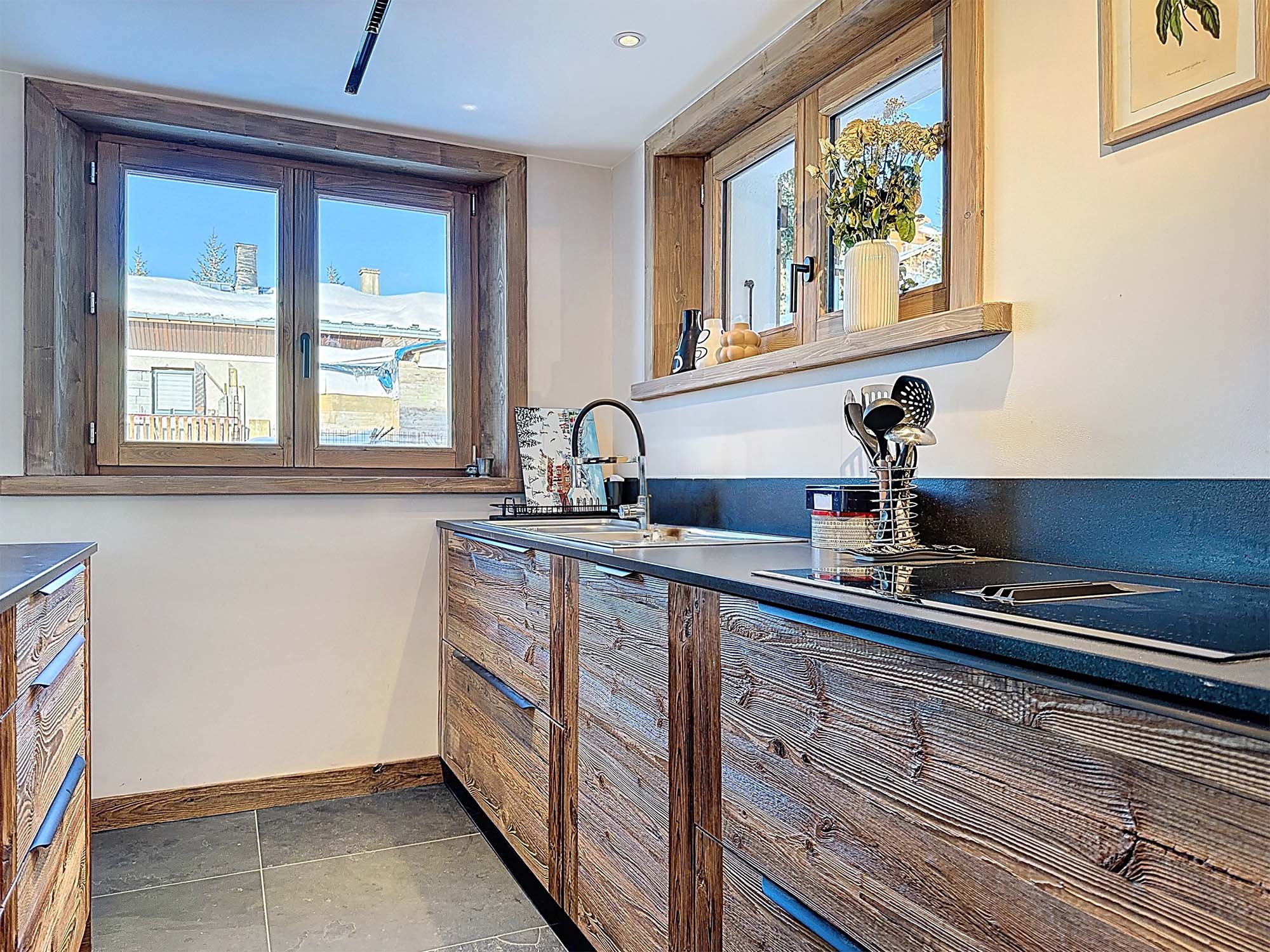image Contemporary open-plan kitchen with premium appliances and rustic wood finishes, perfectly designed for convivial moments after a day on the pistes.