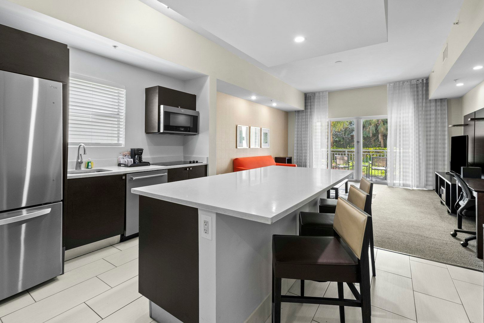 image Sleek kitchen with a large island, stainless steel appliances, and seating for casual dining.