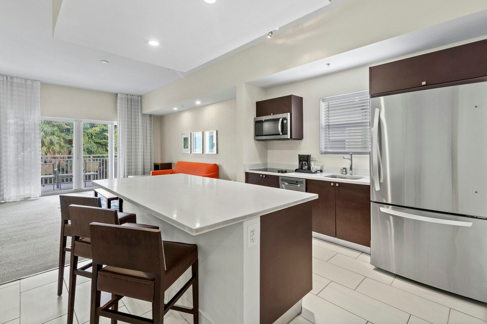 image Modern kitchen featuring a spacious island, stainless steel appliances, and seating for casual meals.