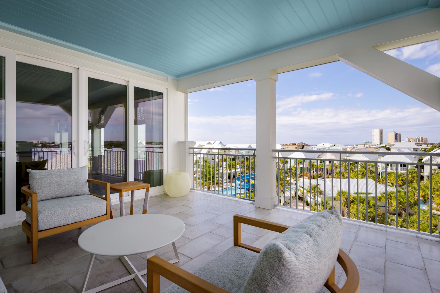 image A balcony seating area invites you to unwind, featuring contemporary furniture beneath a charming blue ceiling, ideal for enjoying coastal views.