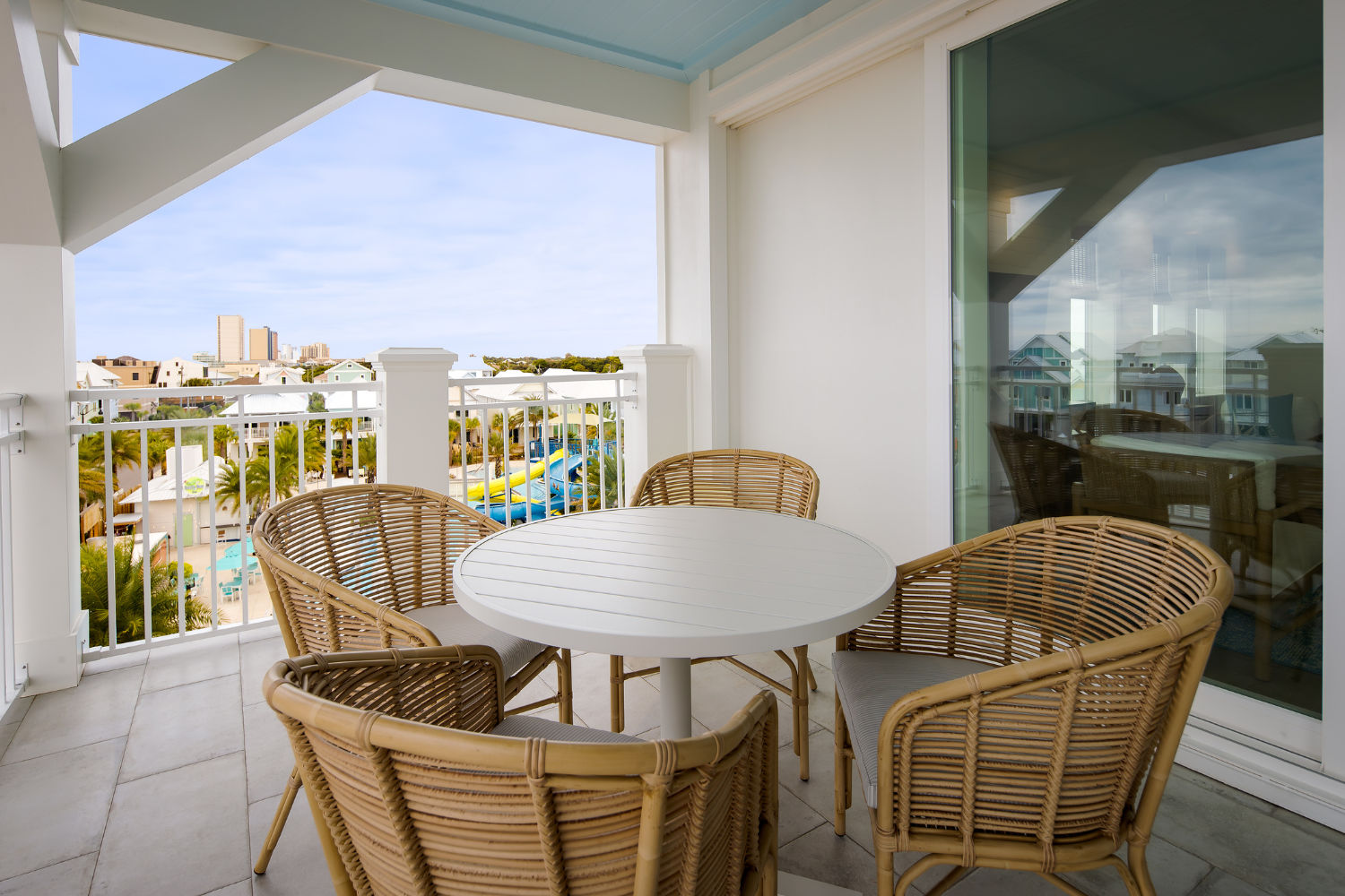 image A charming outdoor dining area with rattan chairs and a white round table, perfect for enjoying meals with a view.