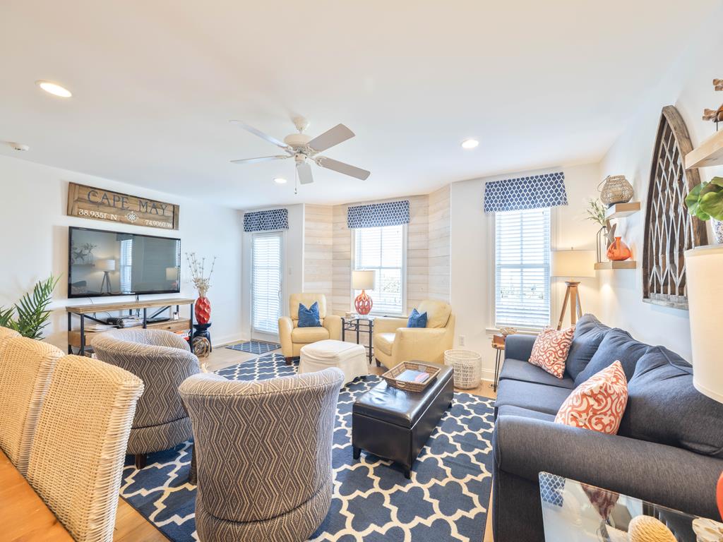 image Bright living room with sectional sofa, accent chairs, patterned area rug, and multiple windows.