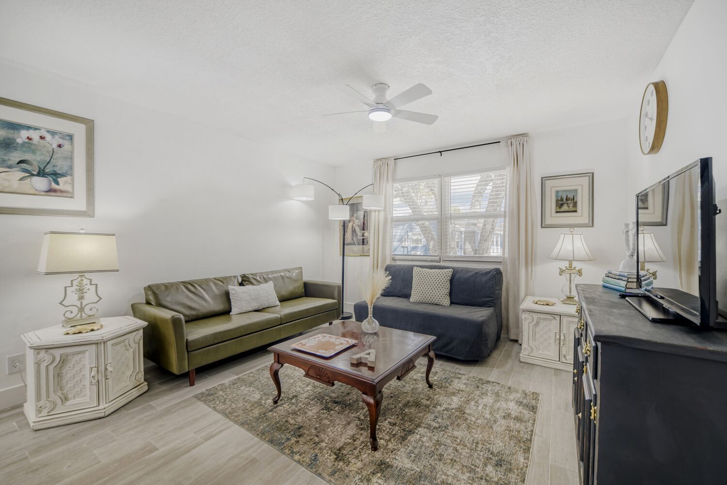 image The sunny living room features a comfortable green sofa and a blue couch, paired with elegant decor and a wooden coffee table, creating a cozy gathering space.