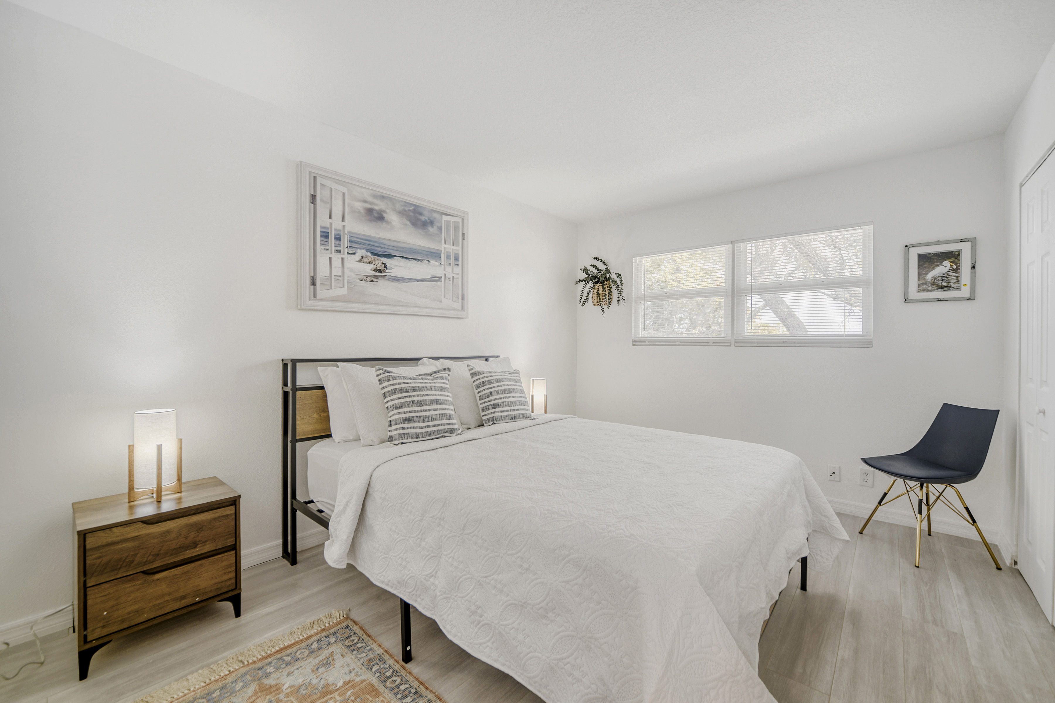 image Airy bedroom with a queen bed, soft lighting, and large windows letting in natural light.