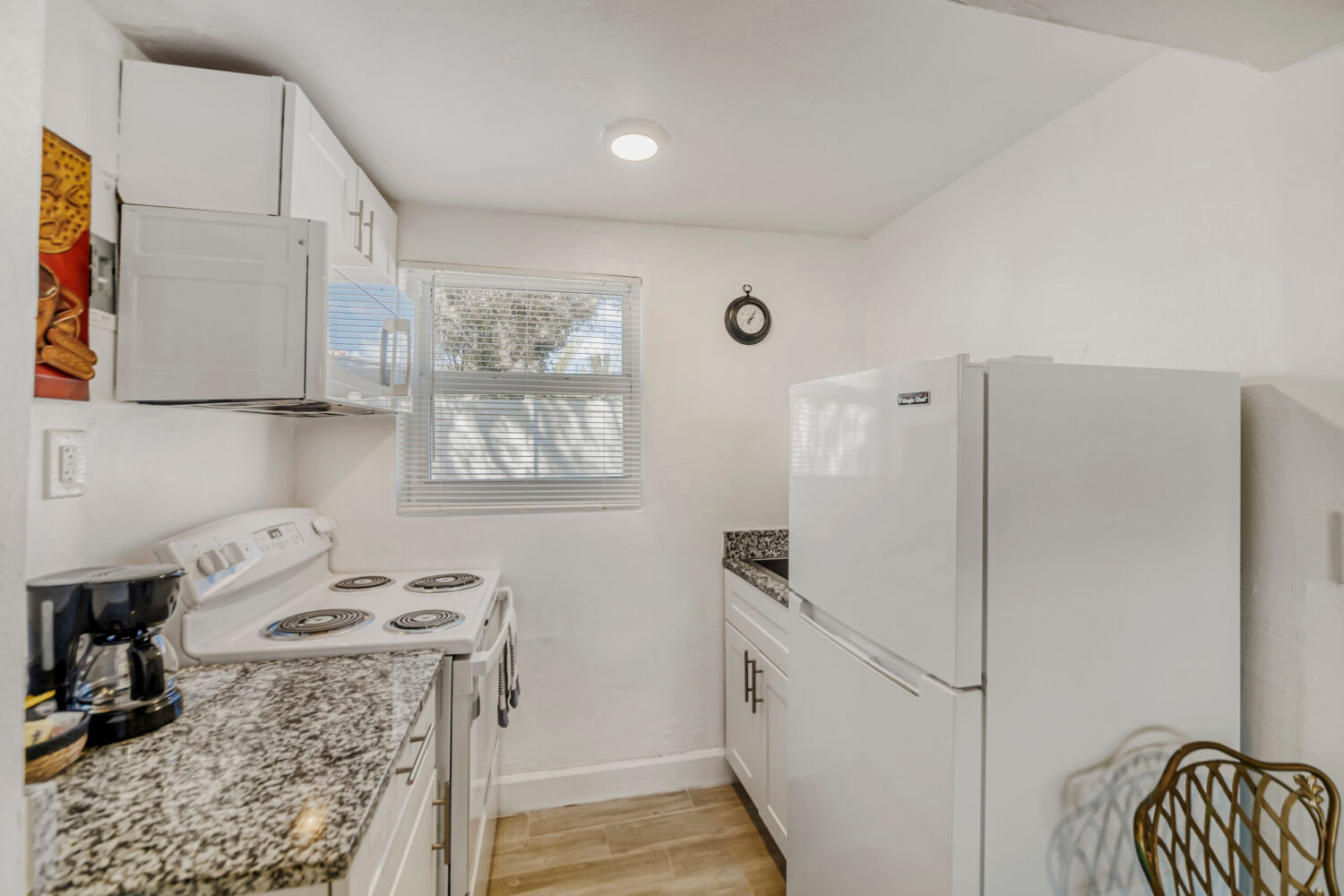 image Kitchenette with a stovetop, microwave, refrigerator, and upper cabinets for storage.