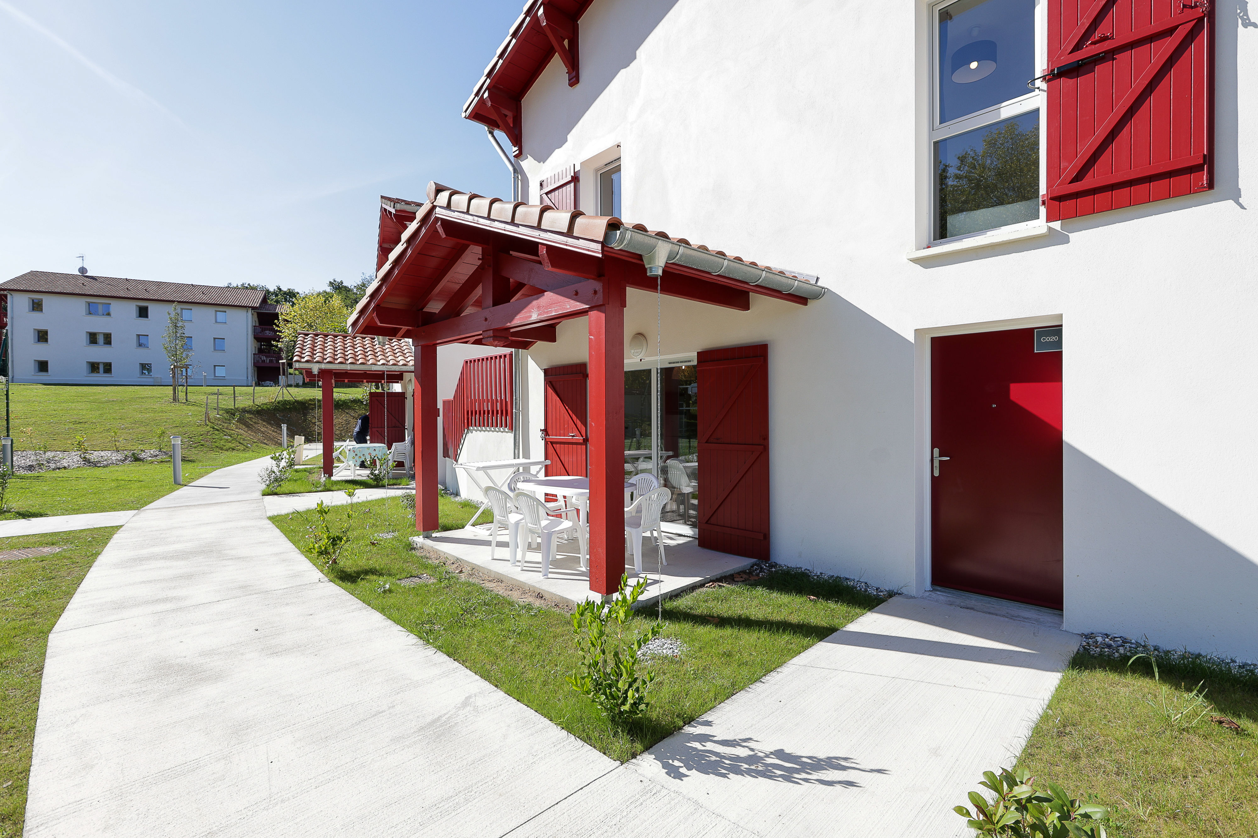 image Your home away from home — the signature red-and-white Basque architecture of Le Domaine d'Uhaina, set among well-maintained green surrounds.