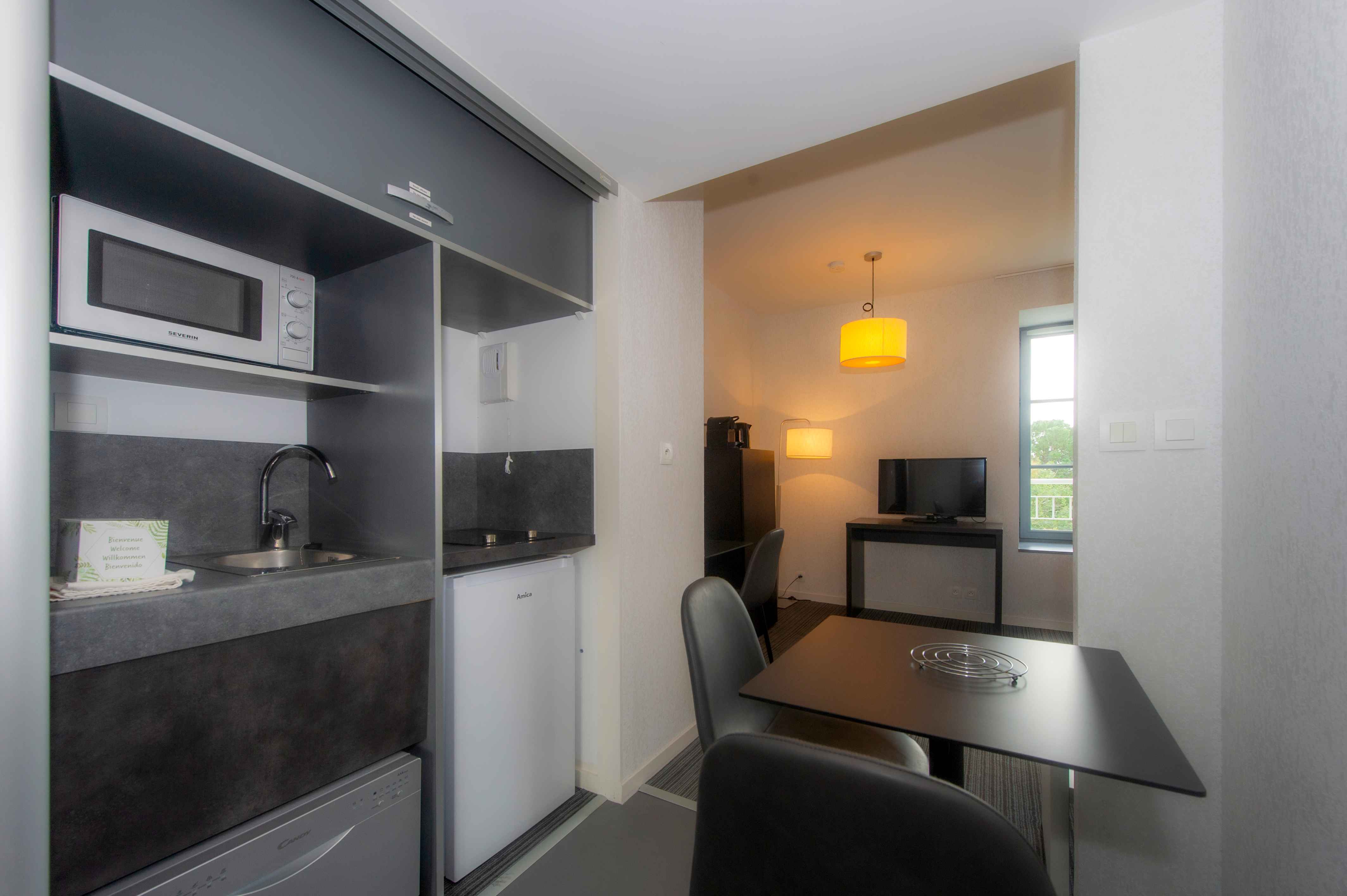 image Compact kitchenette with microwave, stovetop, and a small desk — everything needed for a comfortable self-catered stay.
