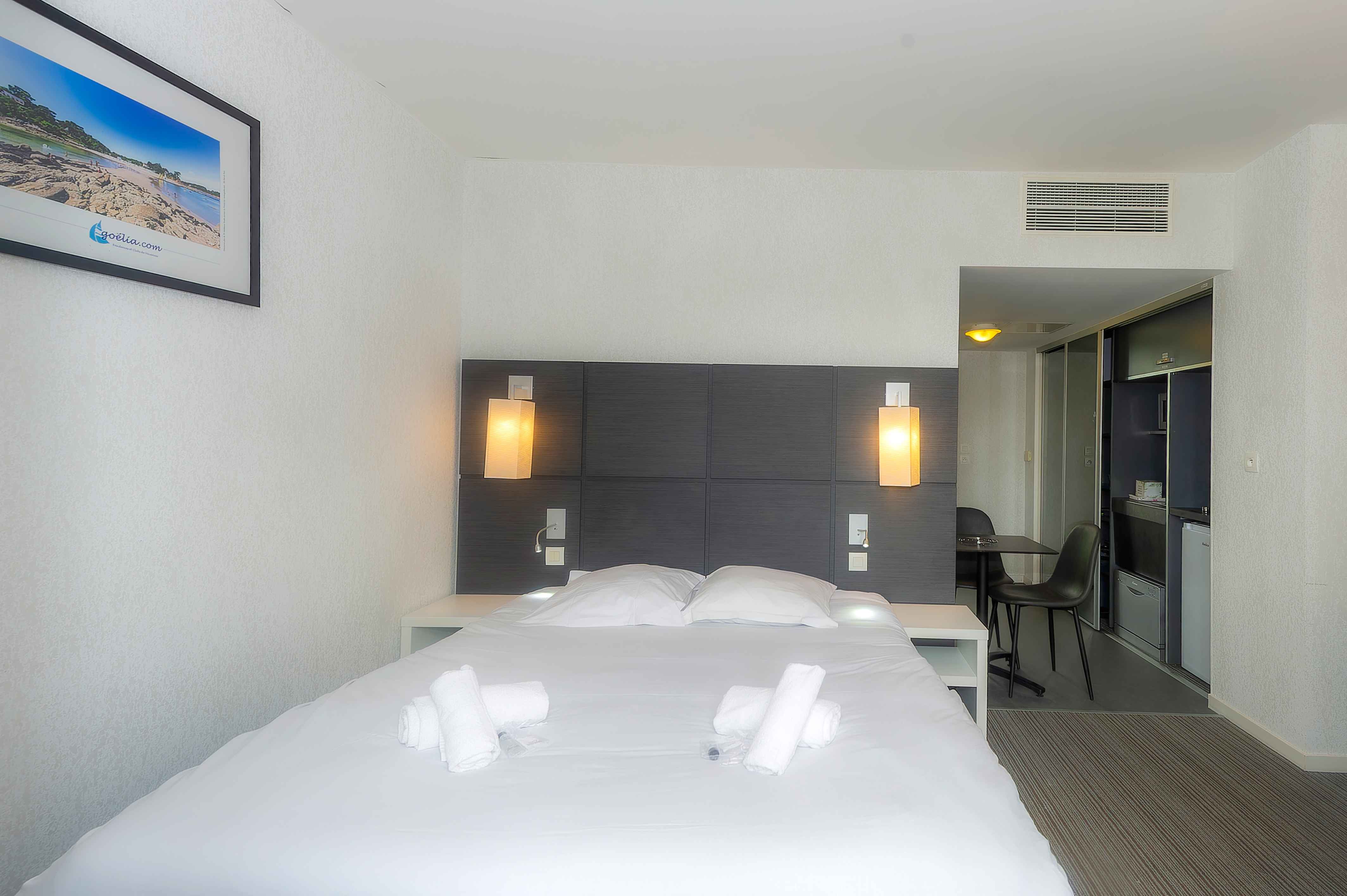 image Grey upholstered headboard, white linens, and a dining area in the background — a well-laid-out studio a short walk from Pont-Aven's galleries and the Aven river.