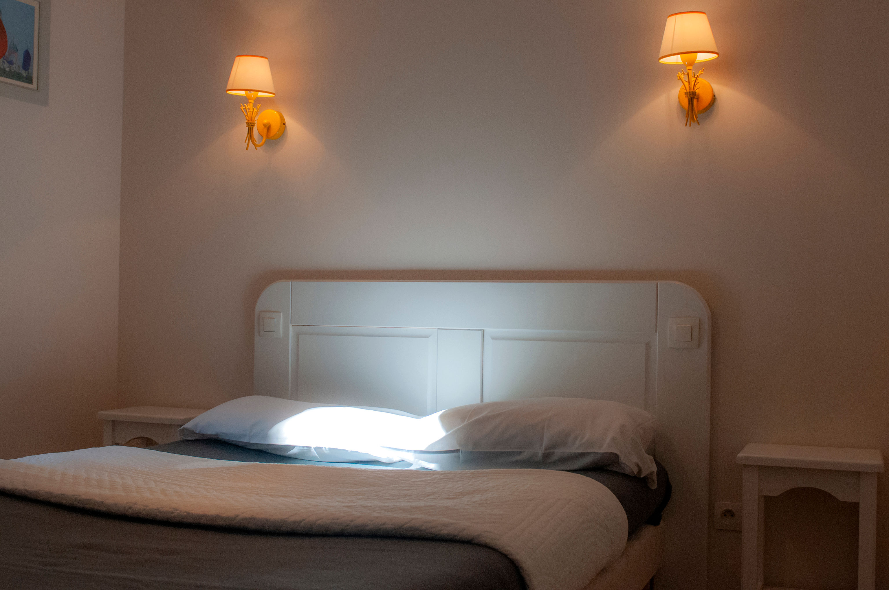 image Separate double bedroom with white headboard, wall sconces on each side, and a quiet position away from the living space