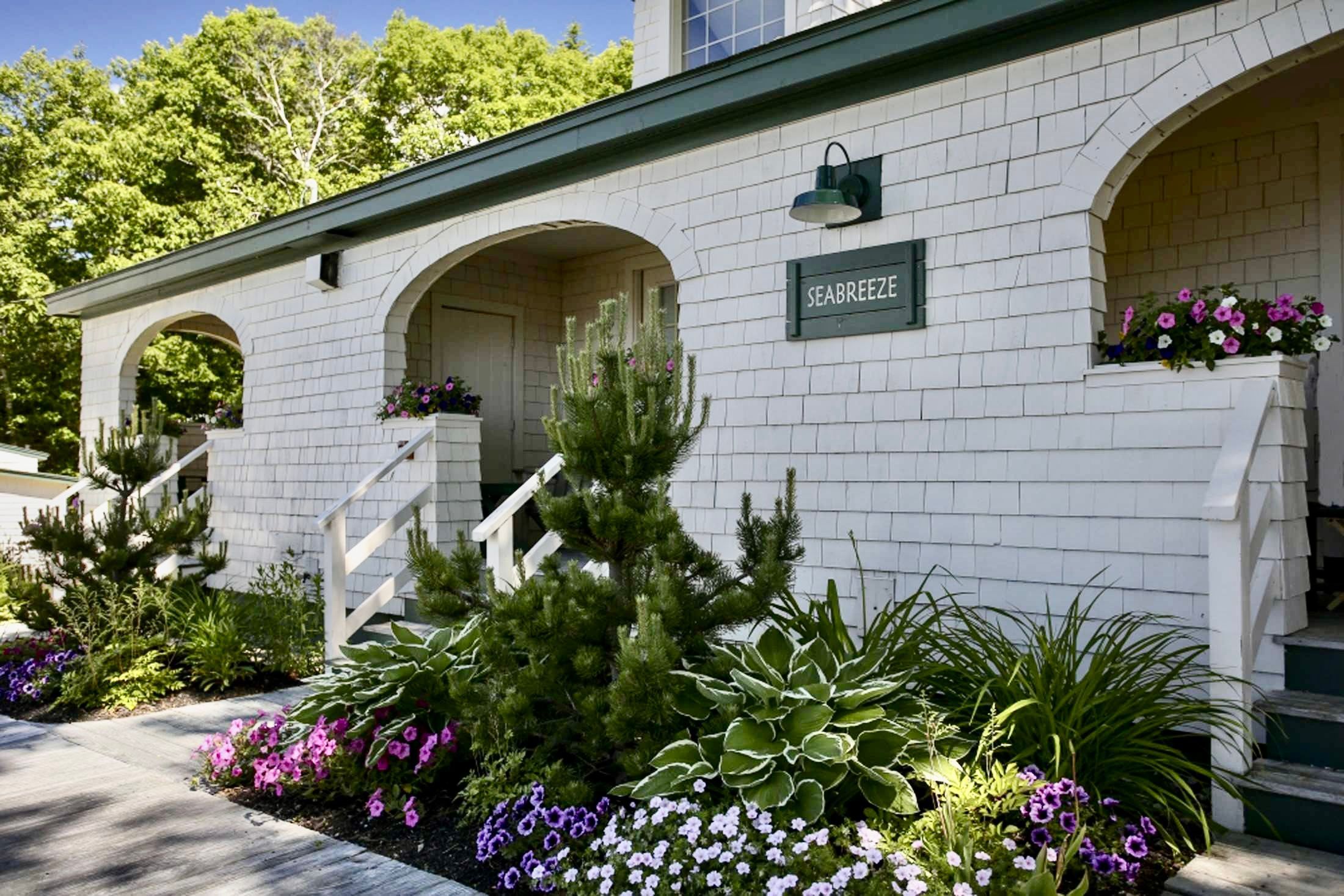 image Wrapped in whitewashed charm and blooming garden beds, this inviting cottage welcomes you with storybook curb appeal.