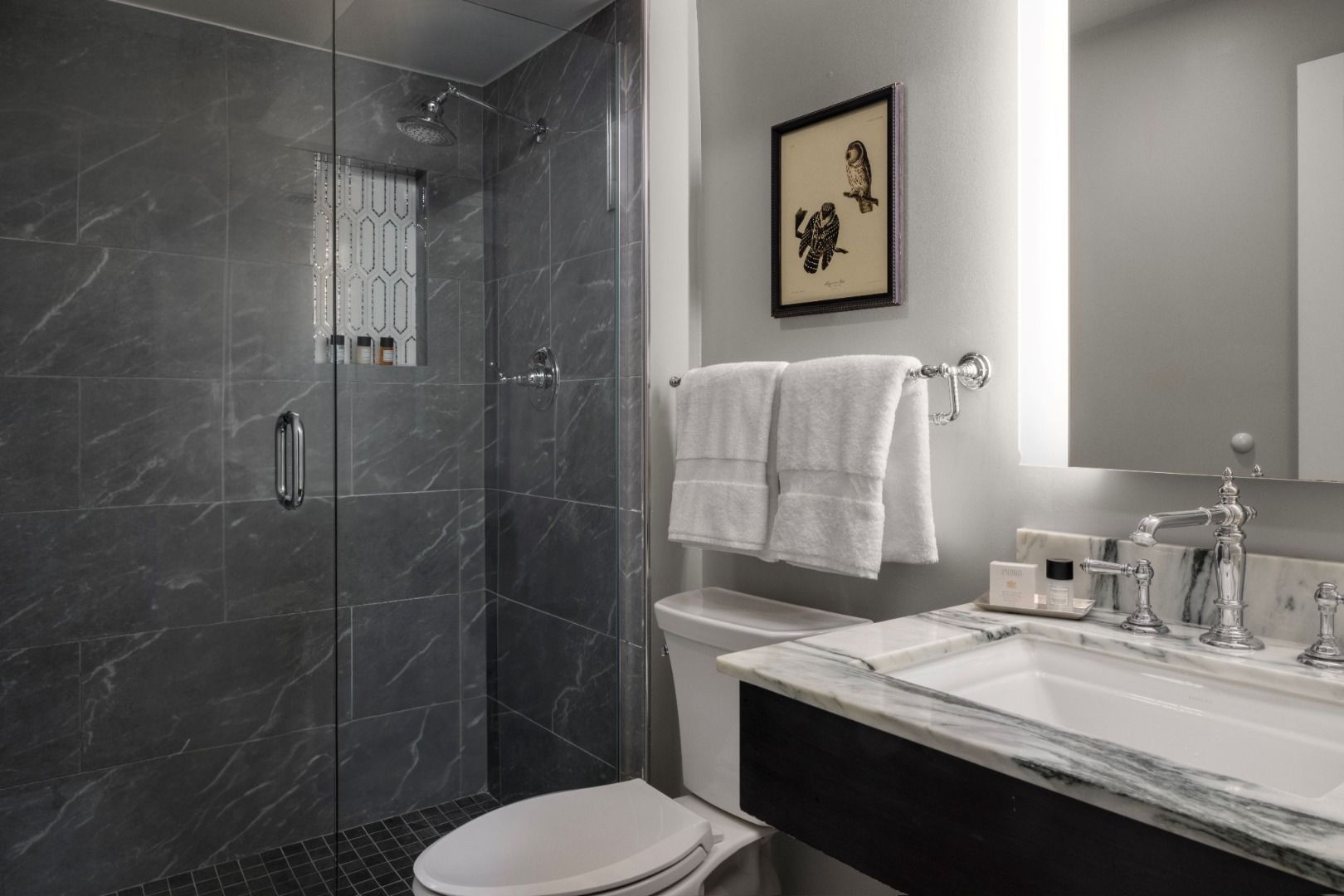 image Elegant bathroom featuring a glass-enclosed rainfall shower, marble vanity, and refined chrome fixtures, creating a sophisticated and serene retreat.