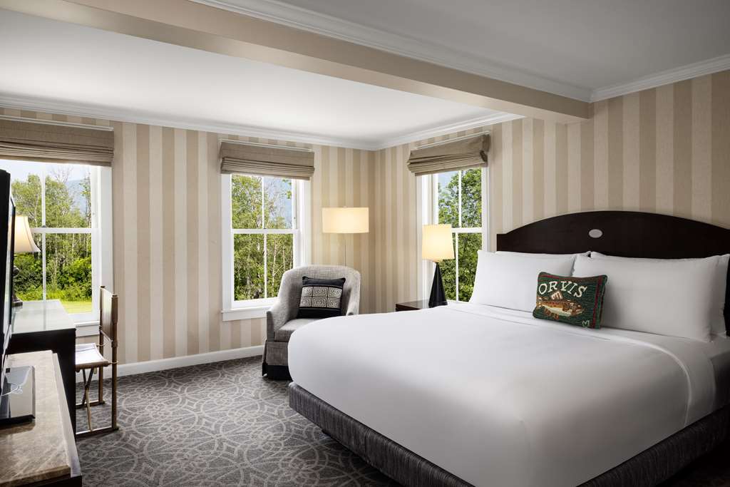image Bright and airy, this guest room showcases a king bed adorned with charming decor, a comfortable sitting area, and large windows that offer beautiful views of the lush greenery outside.