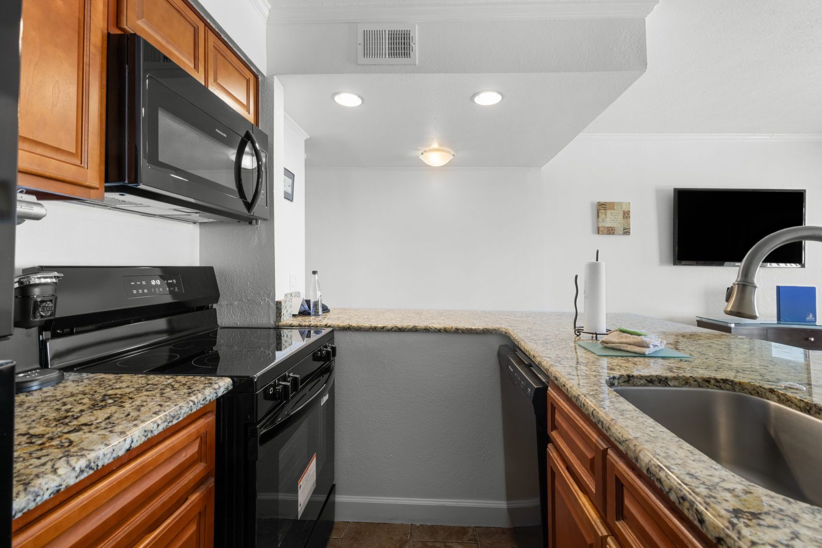 image Cook up delicious meals in this modern kitchen, complete with sleek black appliances and granite countertops.