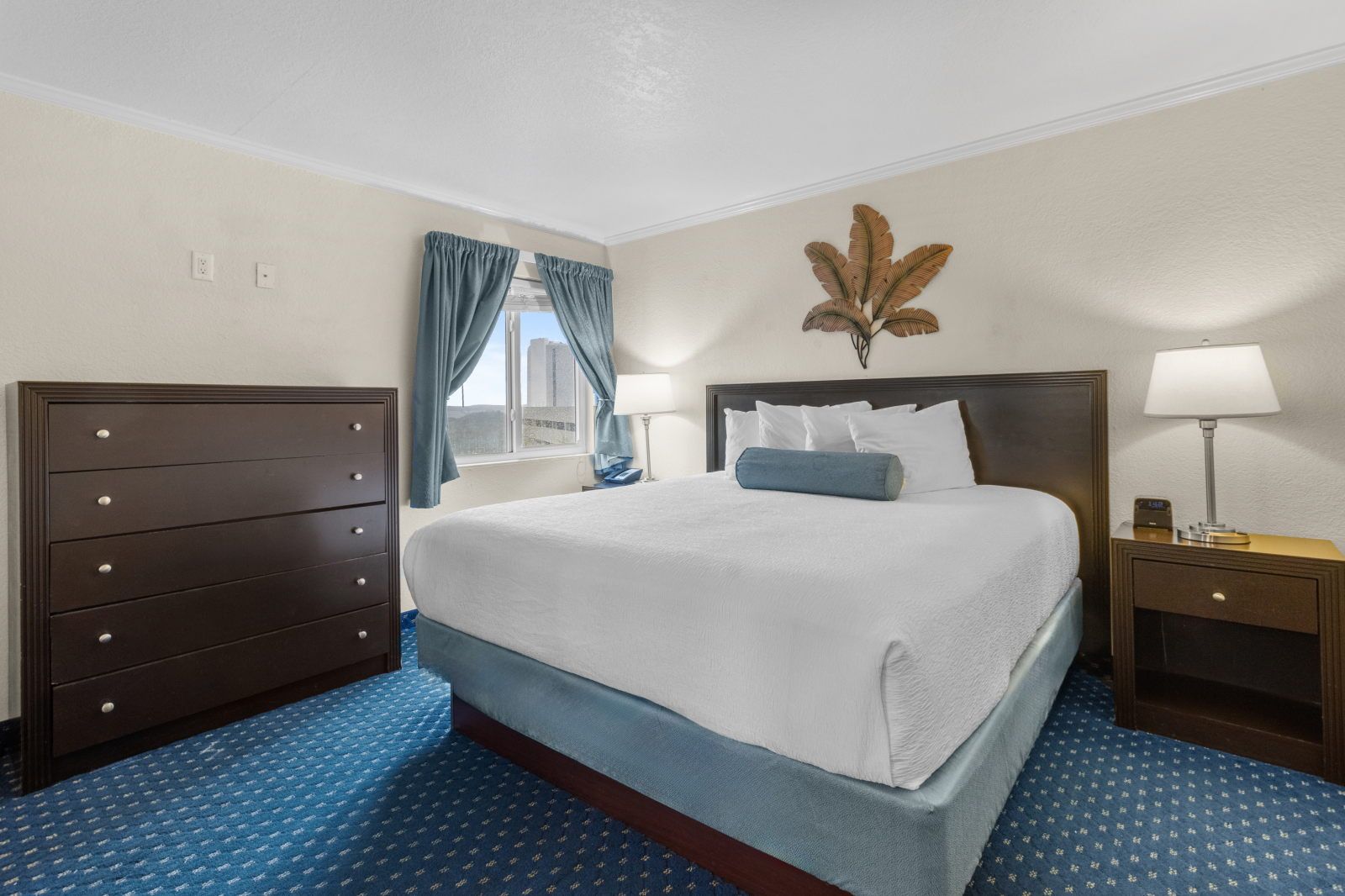 image Relax in a cozy bedroom featuring a plush queen bed, natural light, and stylish decor.