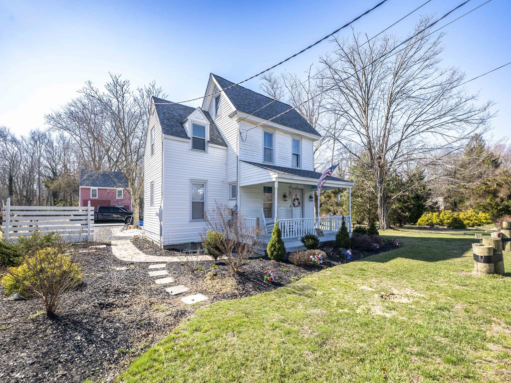 image Your home away from home — a charming white clapboard house set against lush greenery, with a cozy cottage tucked alongside.
