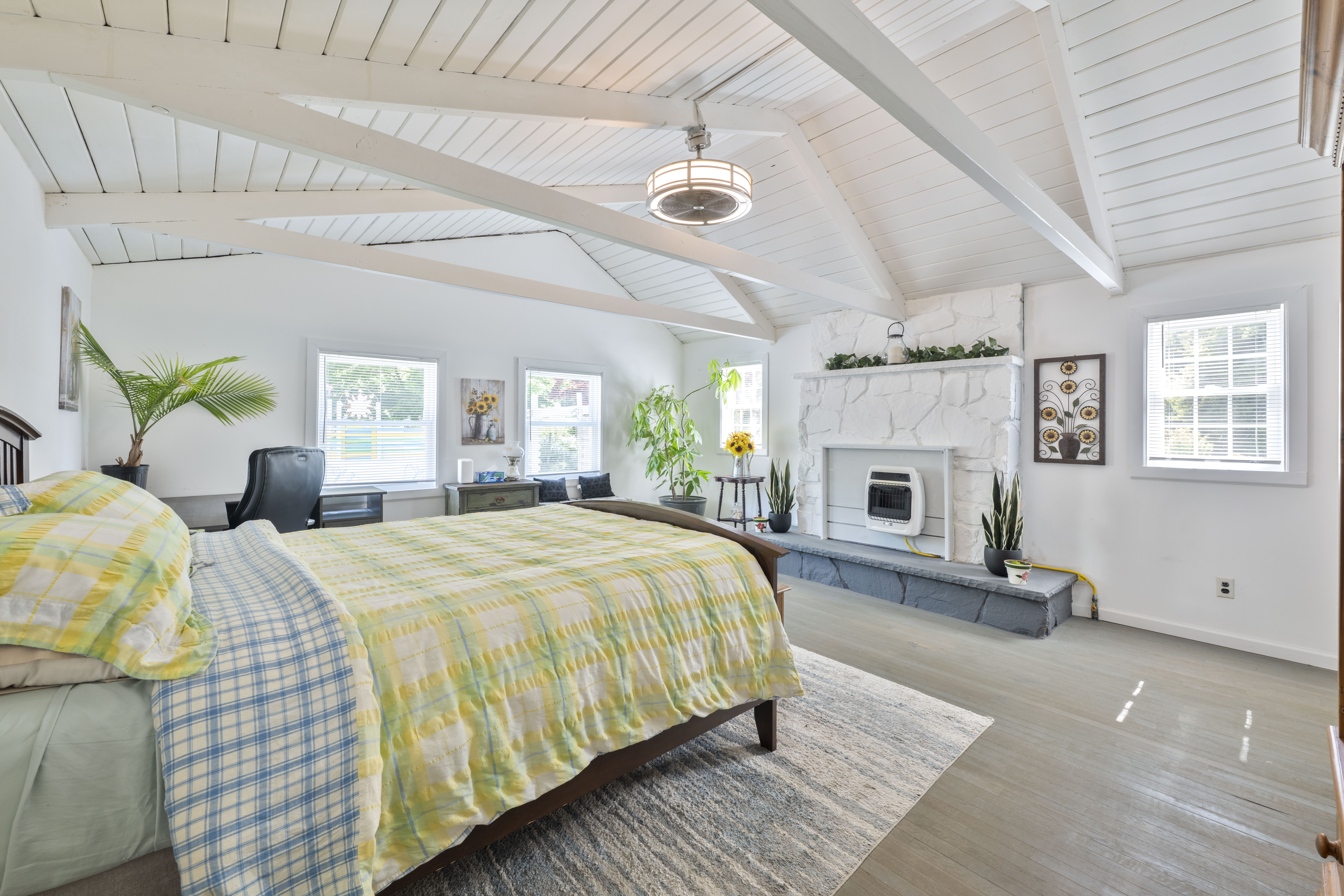image A bright and cheerful bedroom with colourful bedding, a cozy desk nook, and gorgeous exposed beams overhead.