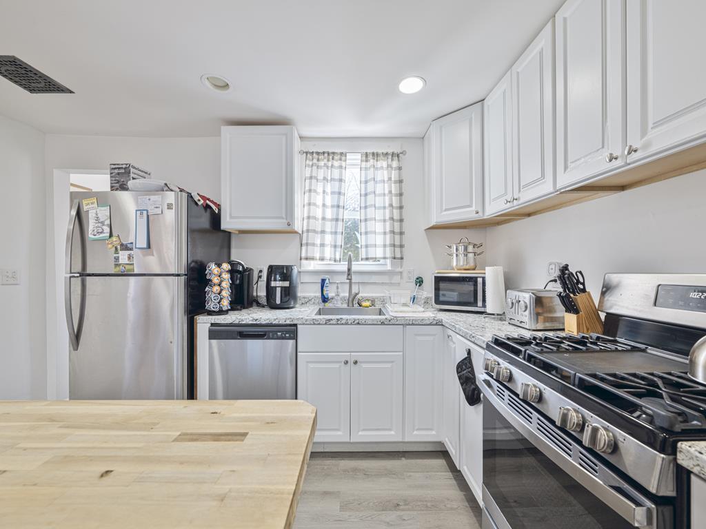 image Full kitchen view showing the refrigerator, dishwasher, stove, and microwave.
