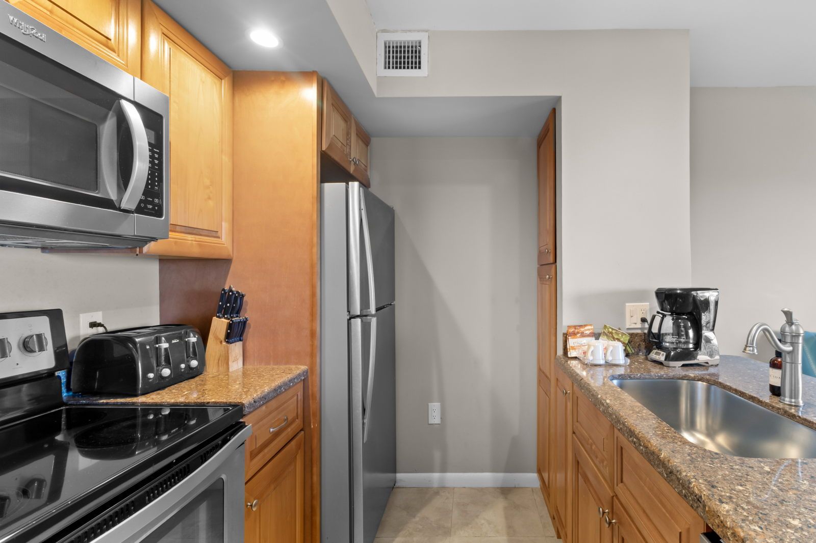 image Prepare meals effortlessly with sleek cabinetry, a spacious countertop, and all the essentials at your fingertips.