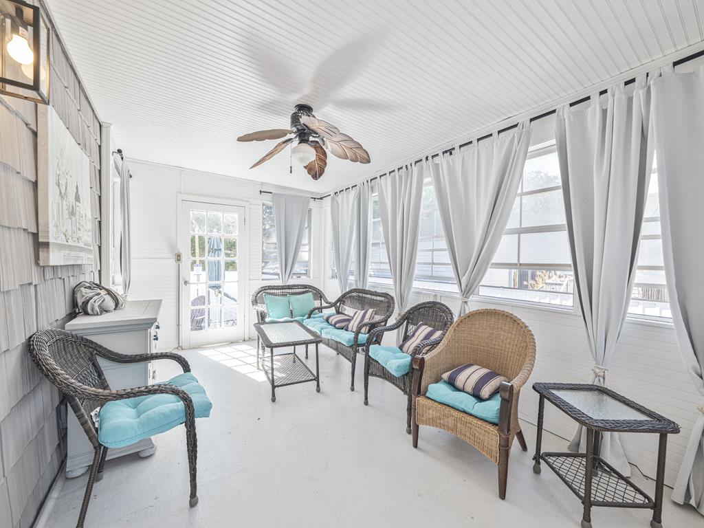 image Unwind in this cozy sunroom, where wicker seating invites you to savor peaceful moments and gentle breezes.