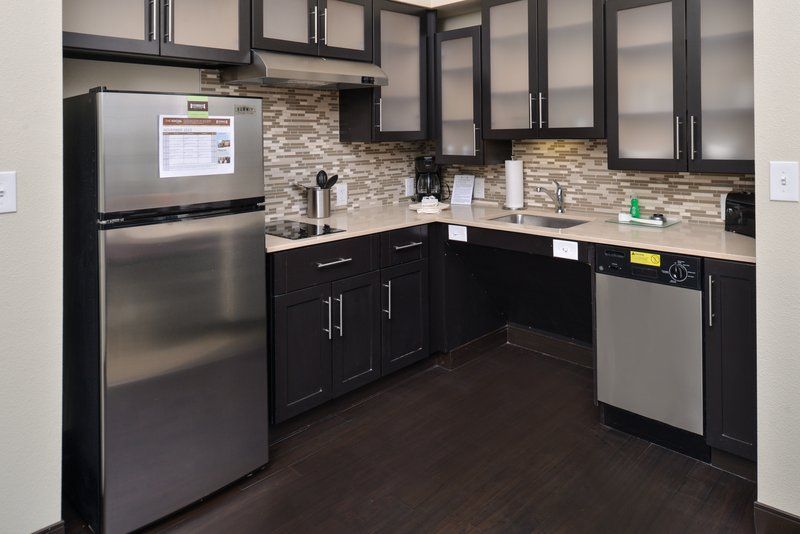 image Full kitchen with stainless-steel appliances, dark wood cabinets, stove, dishwasher, and coffee maker.