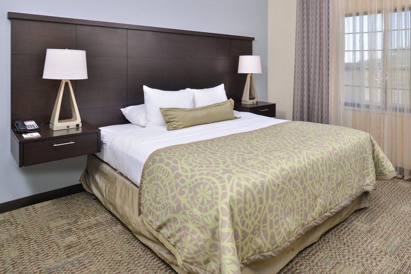image Queen bed with white linens, large windows, and a work desk along the wall — the sofa bed is in the separate living area.