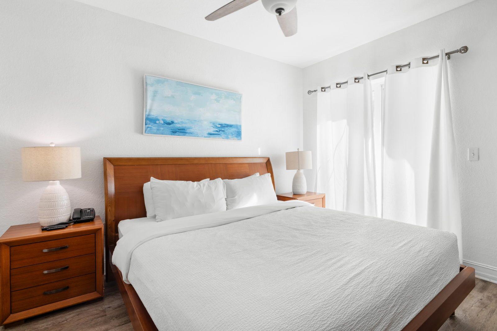 image Relax in a bright bedroom featuring a plush king bed and natural light streaming through sheer curtains.