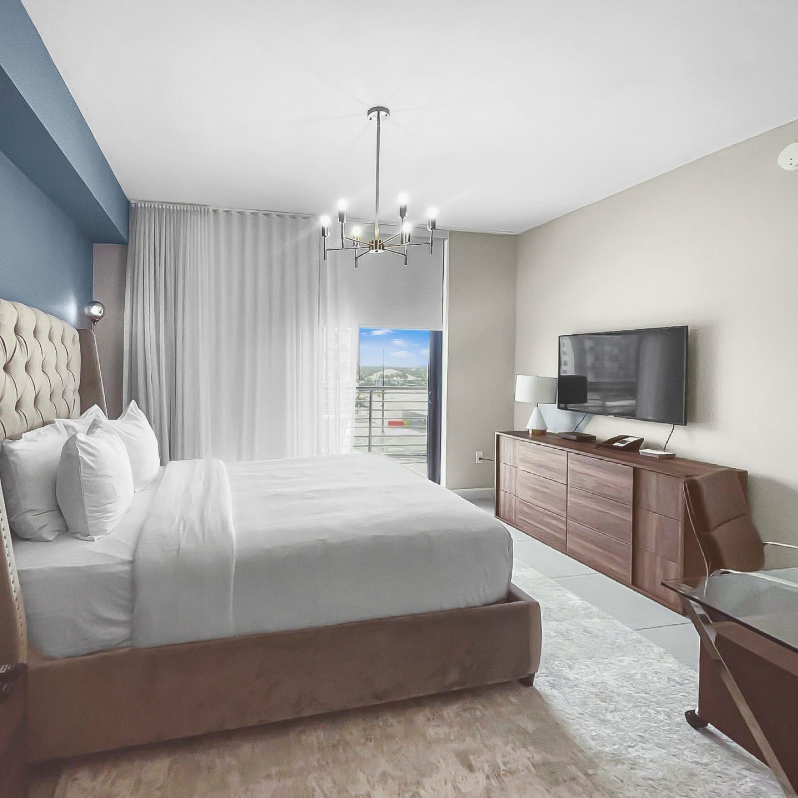 image Relax in a chic bedroom featuring a plush queen bed, modern decor, and a Smart TV.