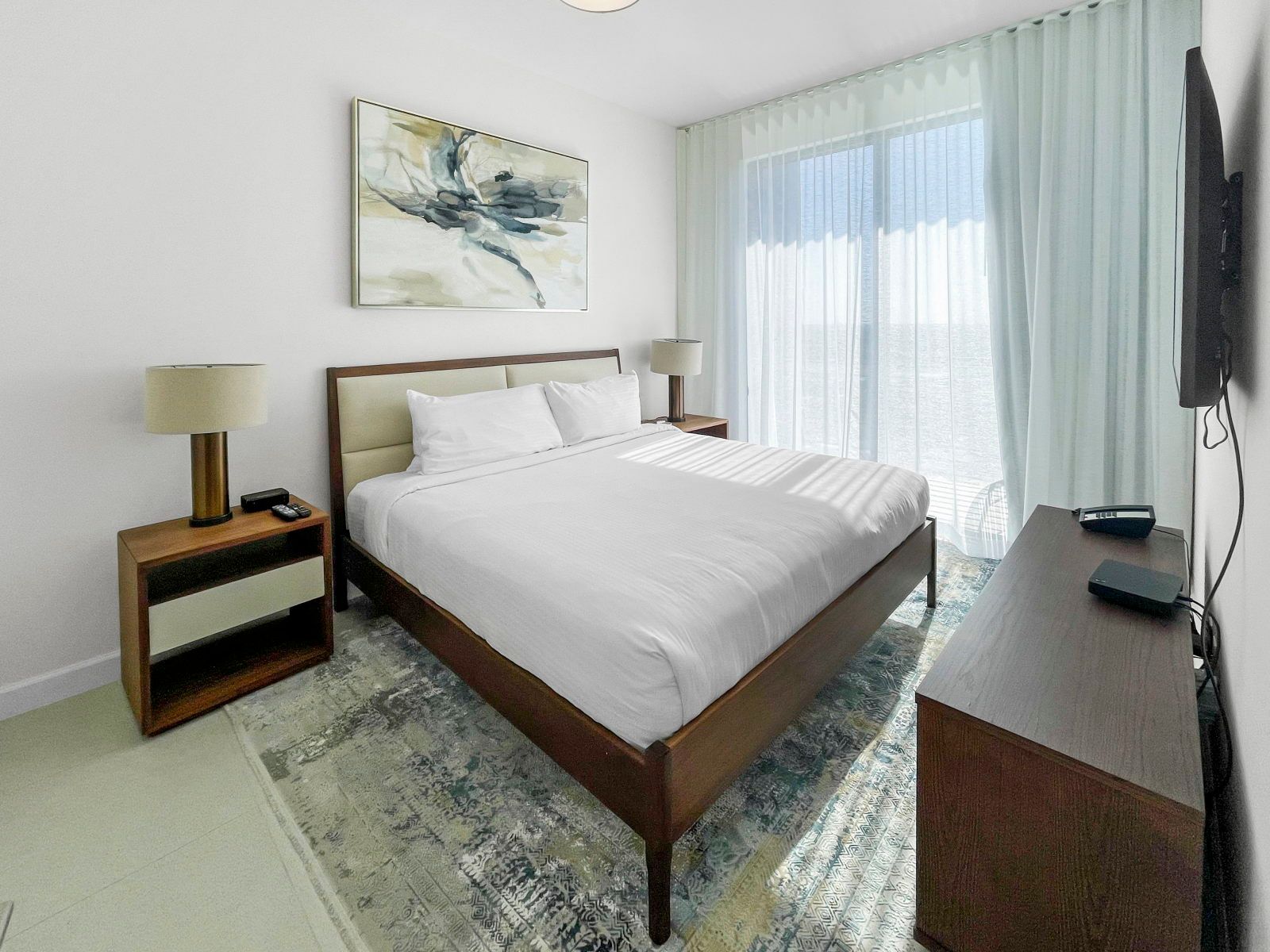 image Discover comfort in a spacious bedroom adorned with thoughtful decor and inviting natural light from large windows.