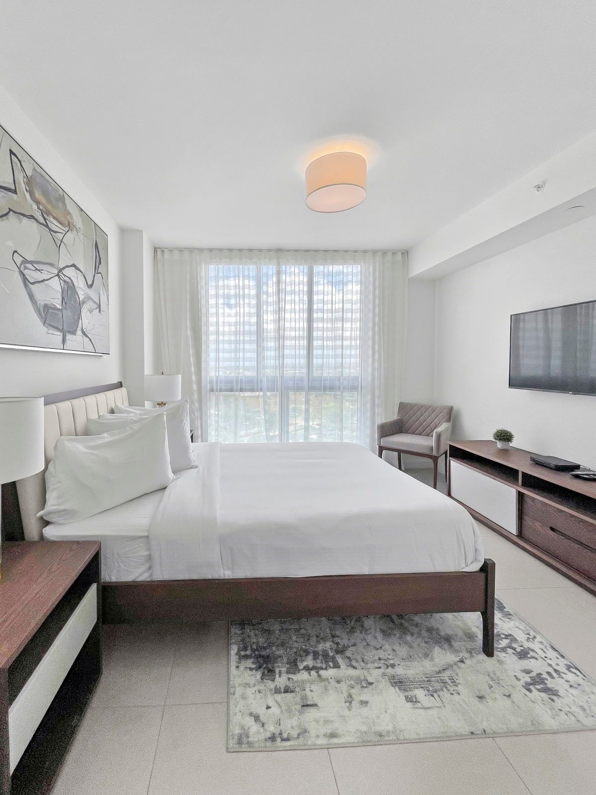 image Relax in a stylish bedroom with plush bedding and natural light filtering through sheer curtains.