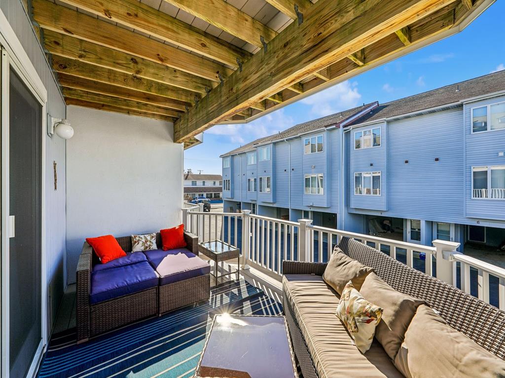 image Covered balcony with dark wicker seating and red and blue cushions, overlooking the neighbourhood