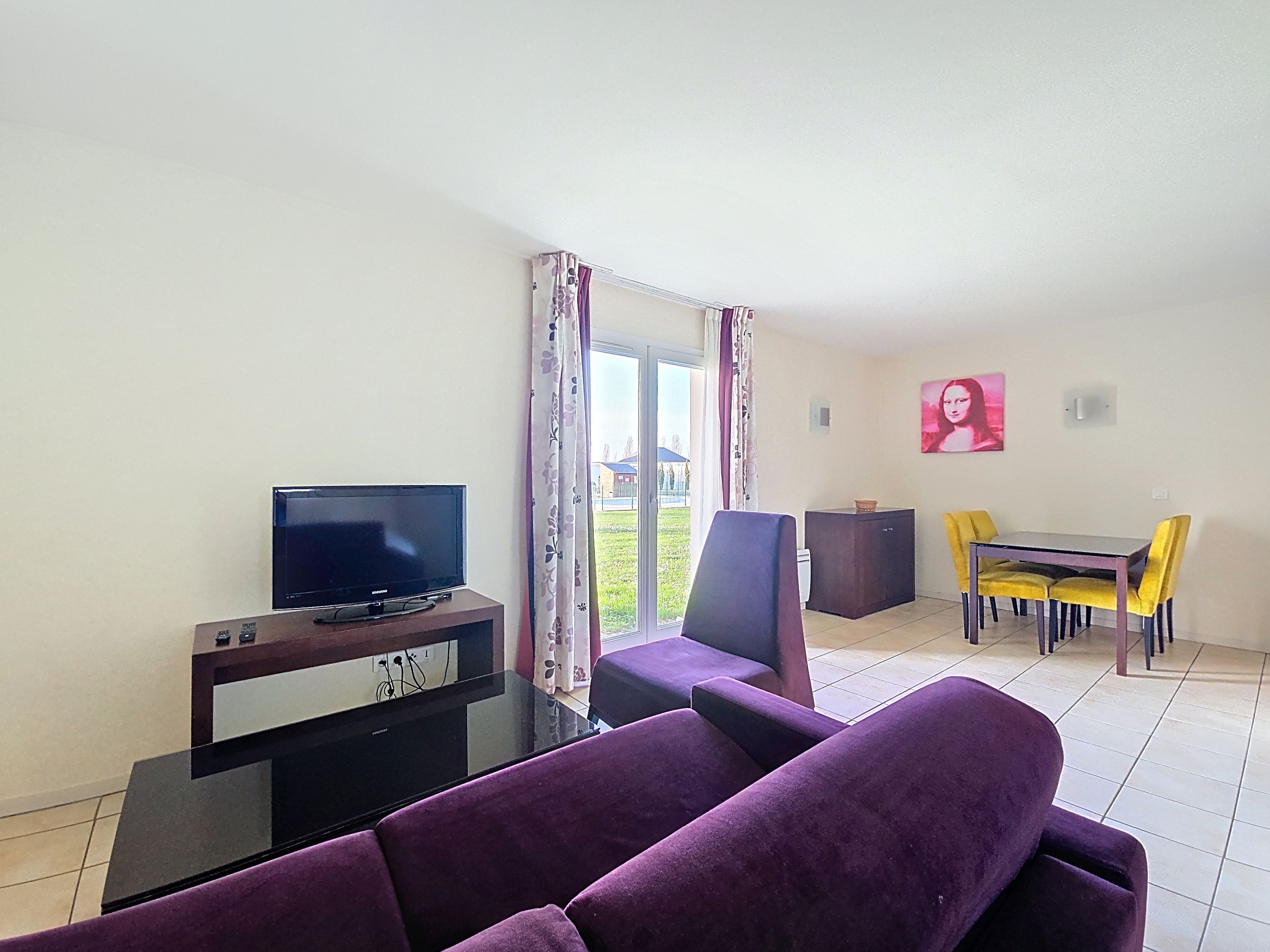 image Living area with purple sofa, black coffee table, TV unit, and dining table set against large windows