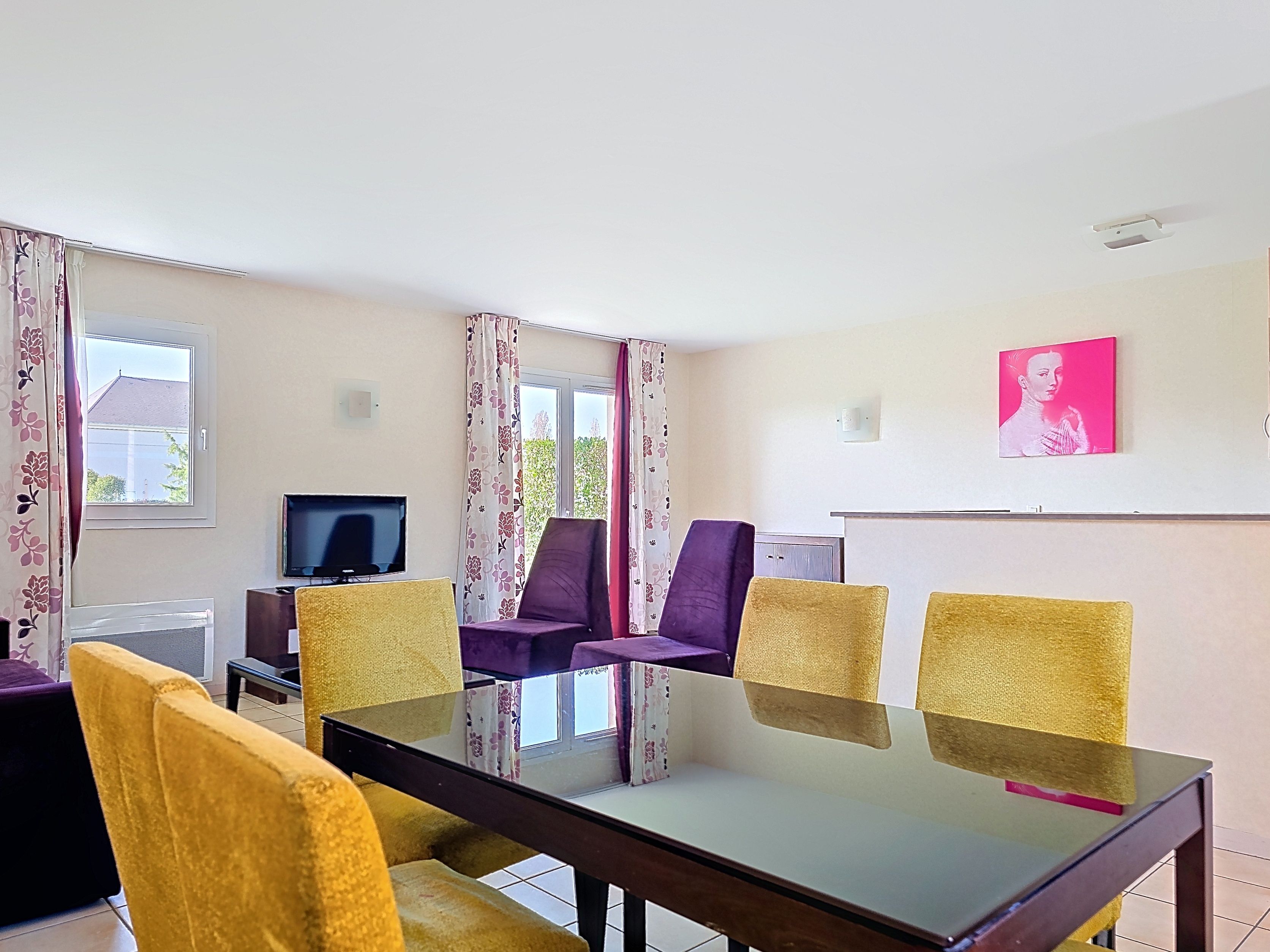 image Ground-floor living area with a glass dining table, yellow velvet chairs, purple sofa, and TV in the corner