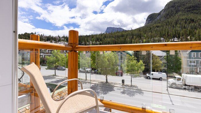 image Balcony chair overlooking tree-lined street with mountain backdrop