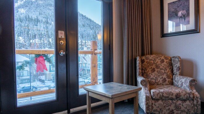 image Snow-dusted mountains and evergreens framed through the balcony doors on a winter afternoon