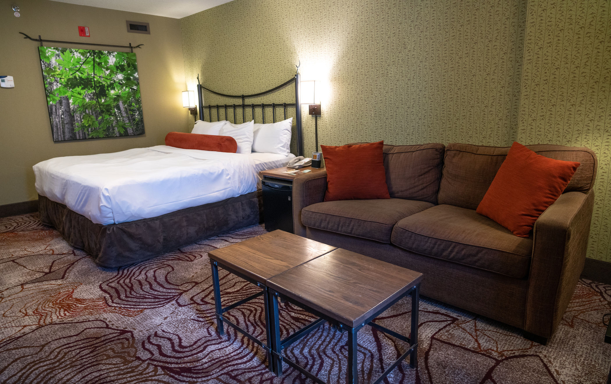 image Upper-floor king room with warm wood tones and earthy décor — private balcony just through the door