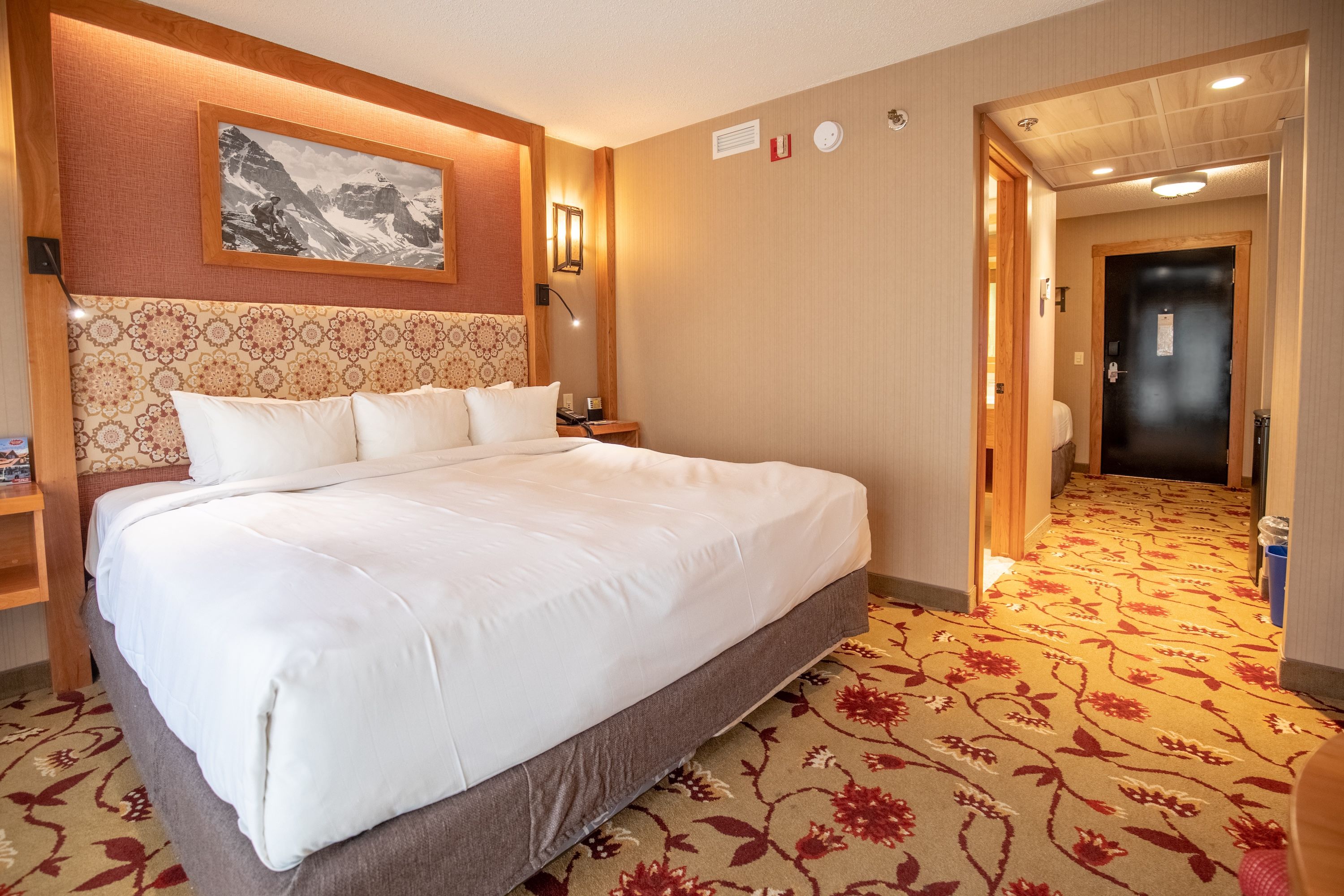 image King Mountain Luxury bed with warm-toned furnishings — wake up to mountain views before heading out to the Banff Gondola