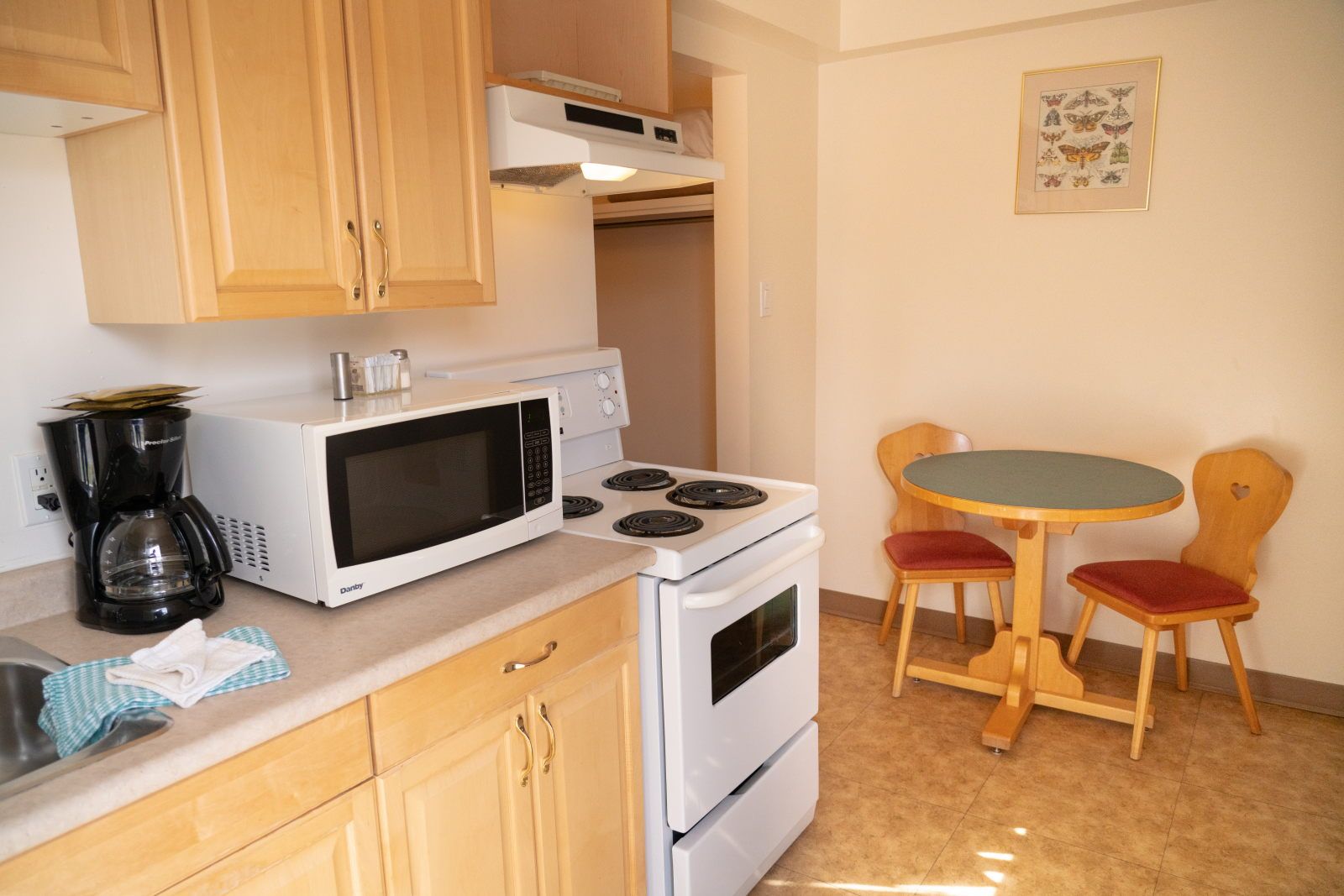 image Light wood kitchen with full stovetop, microwave, coffee maker, and a two-seat dining table