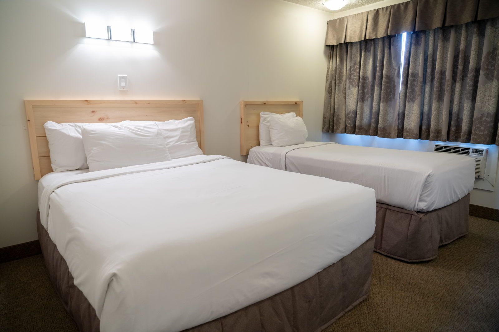 image Queen and twin beds with light wood headboards and white linens — room for two or three guests