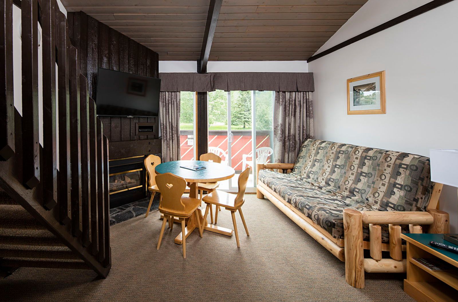 image Living room with log sofa bed, stone fireplace, wall-mounted TV, and sliding door to the patio
